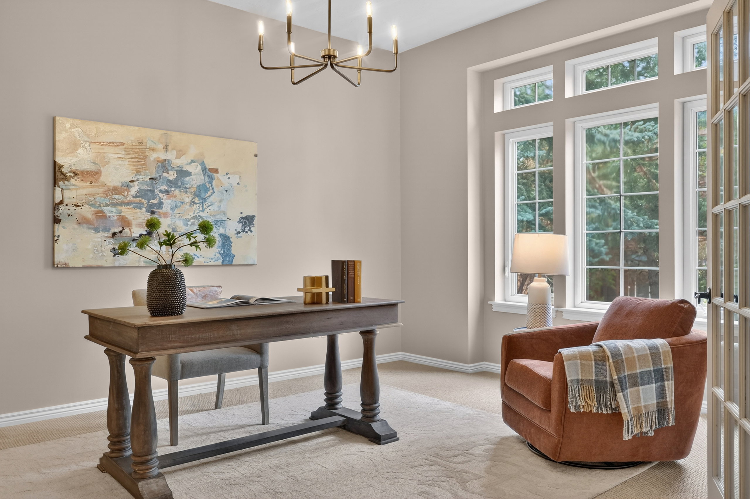 Office space featuring an ornate chandelier, a large multi-pane window with transom accents, light-toned walls, and a light-colored carpet