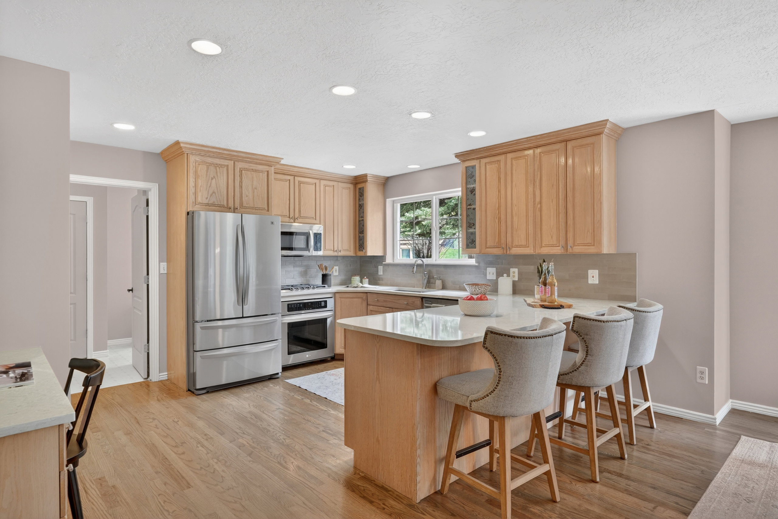 Kitchen featuring light wood cabinetry, stainless steel appliances, recessed lighting, and a kitchen island with seating