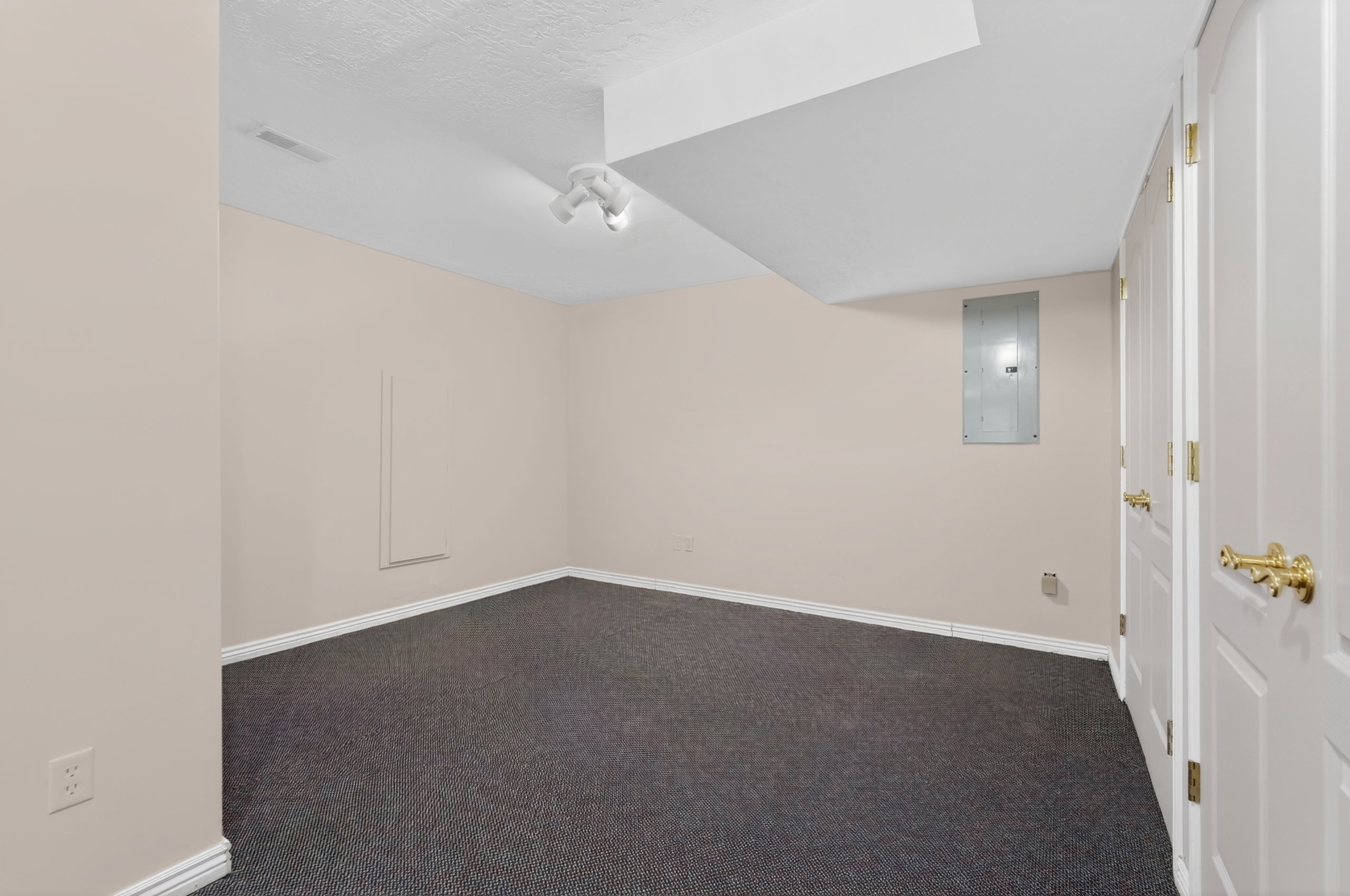 Room featuring textured ceiling, light-toned walls, and dark carpet flooring