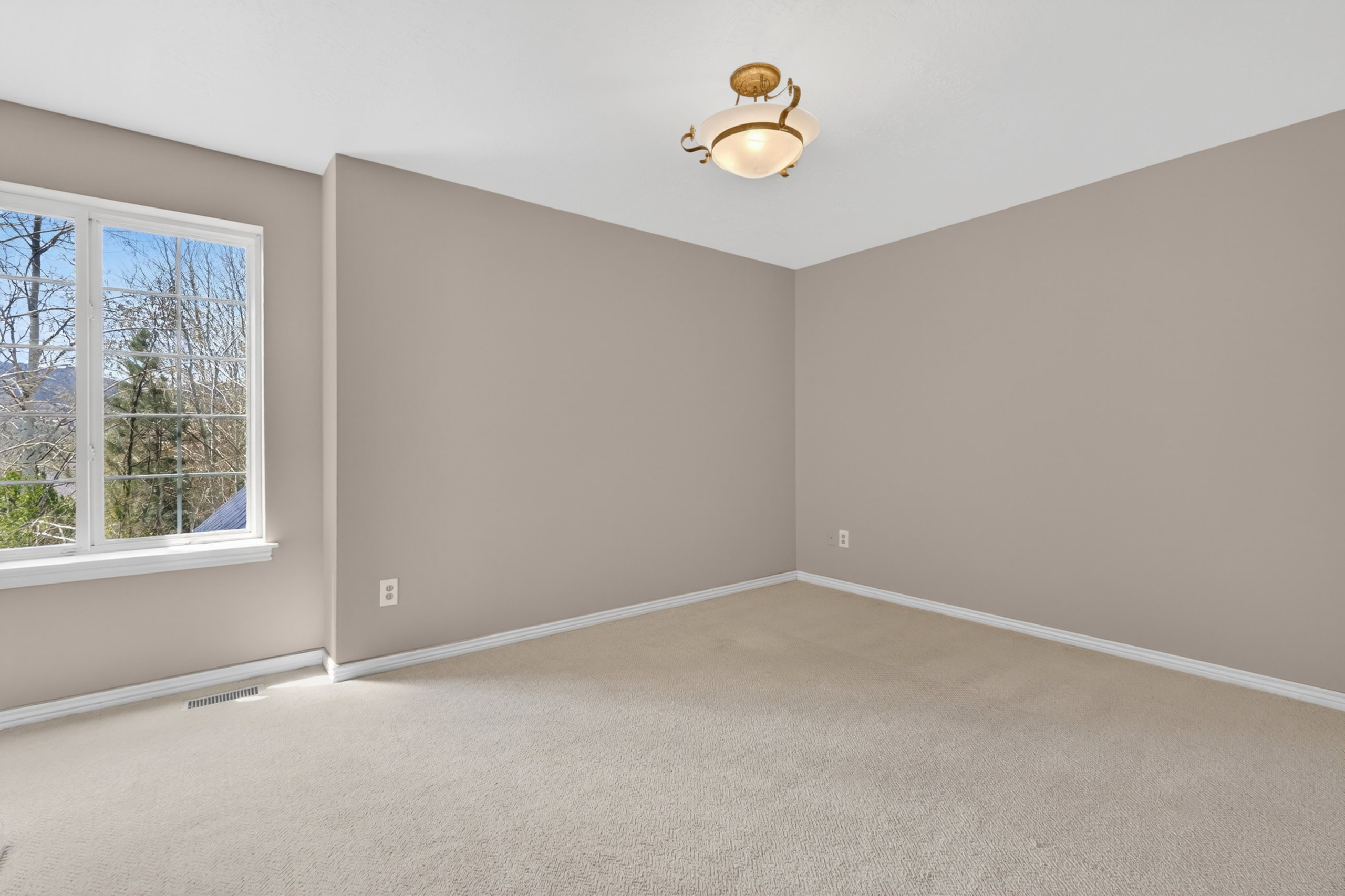 Carpeted room featuring a large window with multiple panes, providing natural light and exterior views