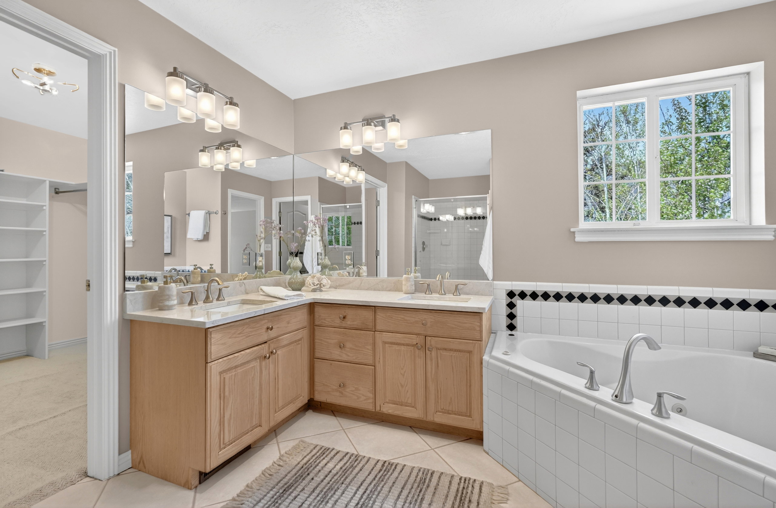 Bathroom featuring a dual vanity with light wood cabinetry and light-toned countertops