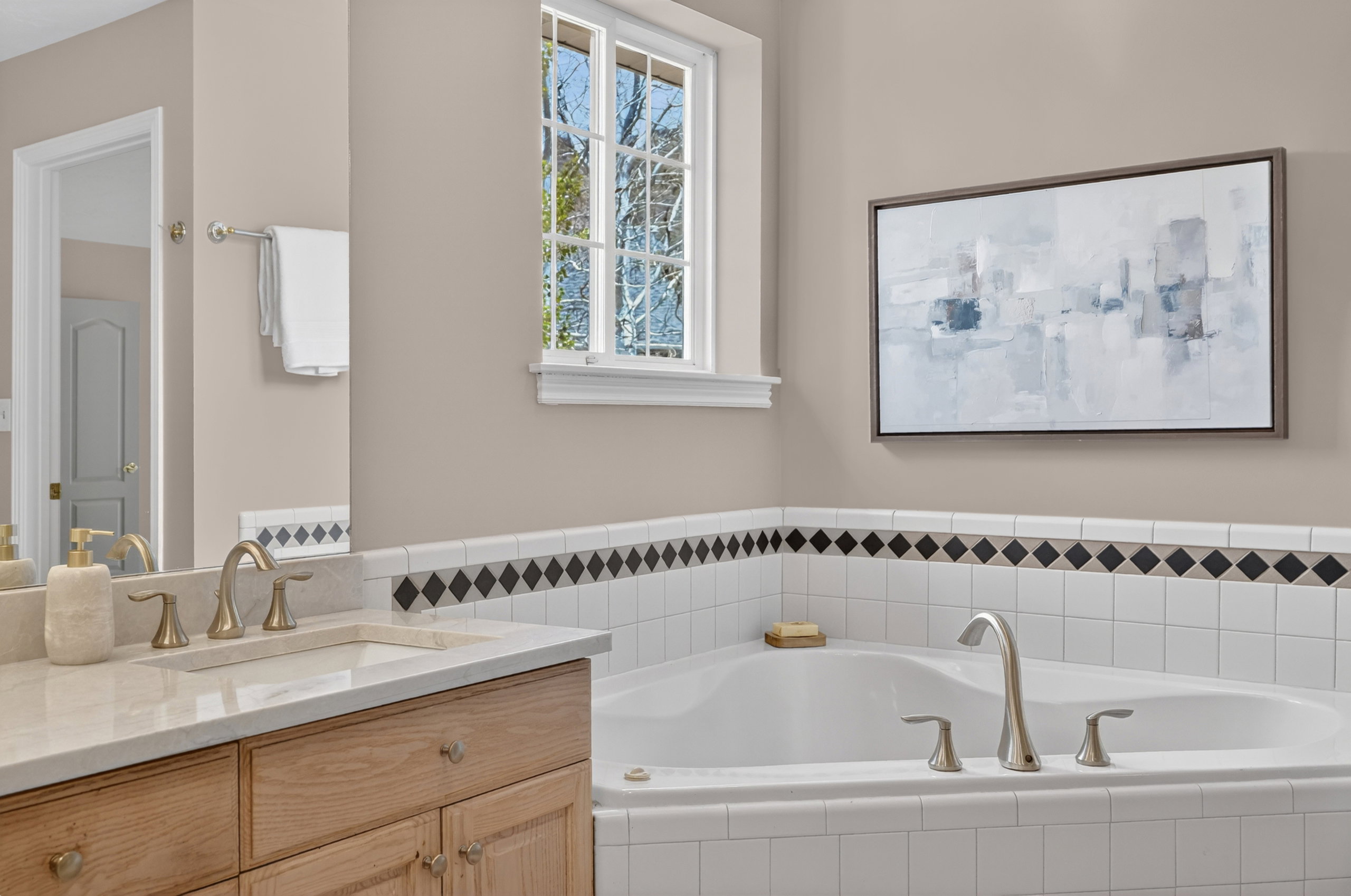 Alcove bathtub with white subway tile surround and black diamond accent