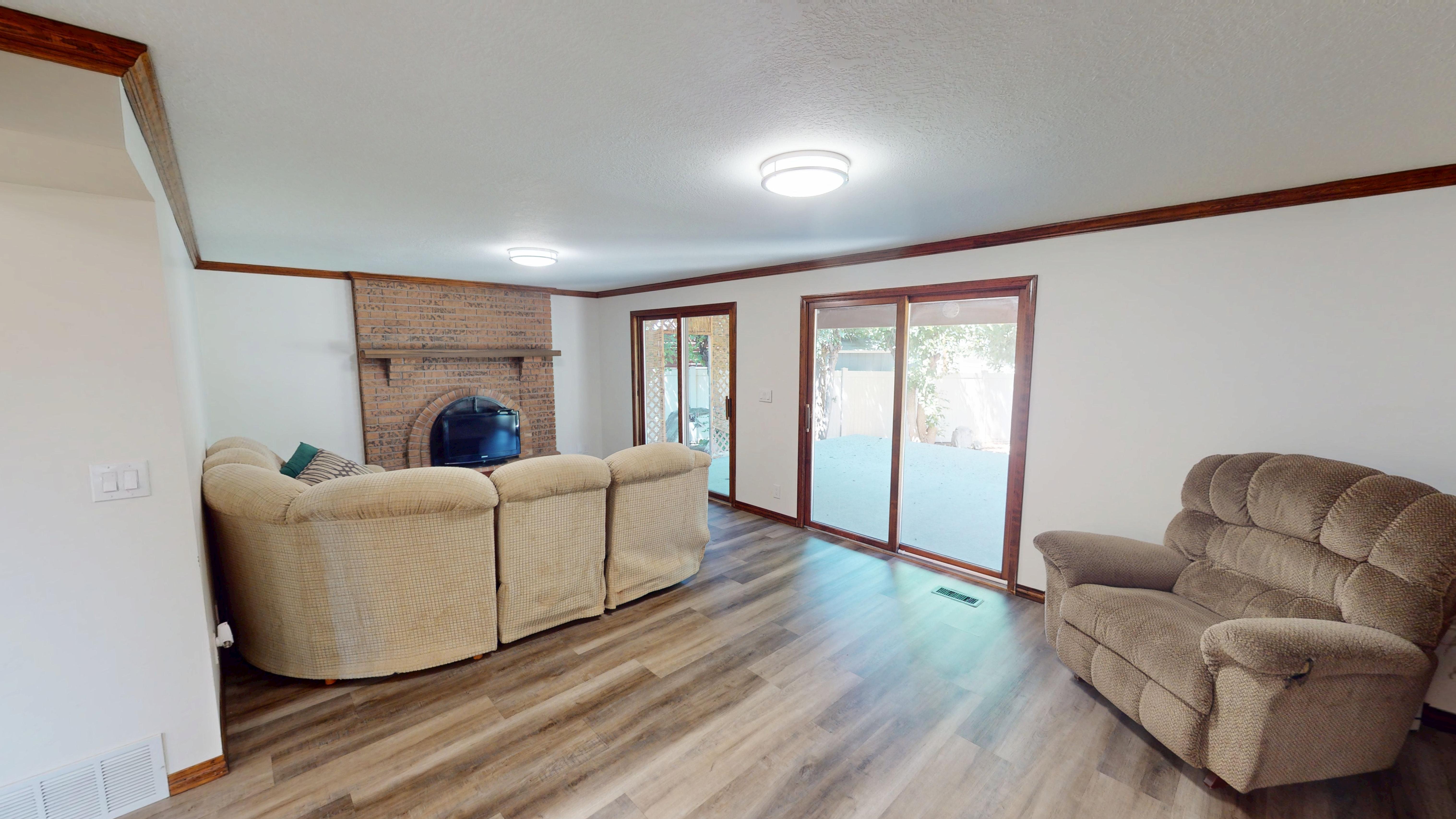 Living area featuring wood-finish flooring, a brick fireplace, and dual sliding glass doors