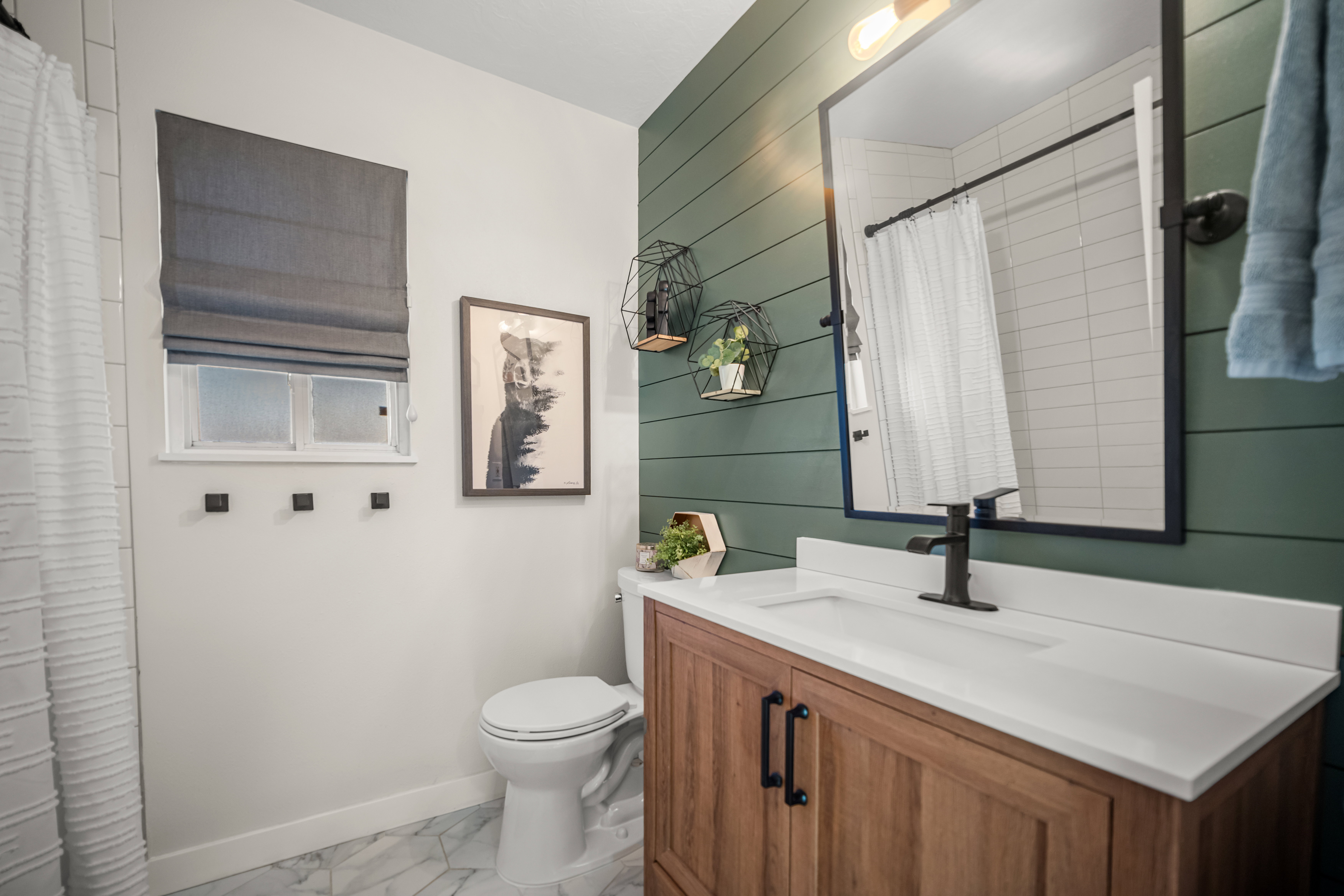 Bathroom featuring wood-finish vanity with white countertop, integrated sink, and matte black faucet