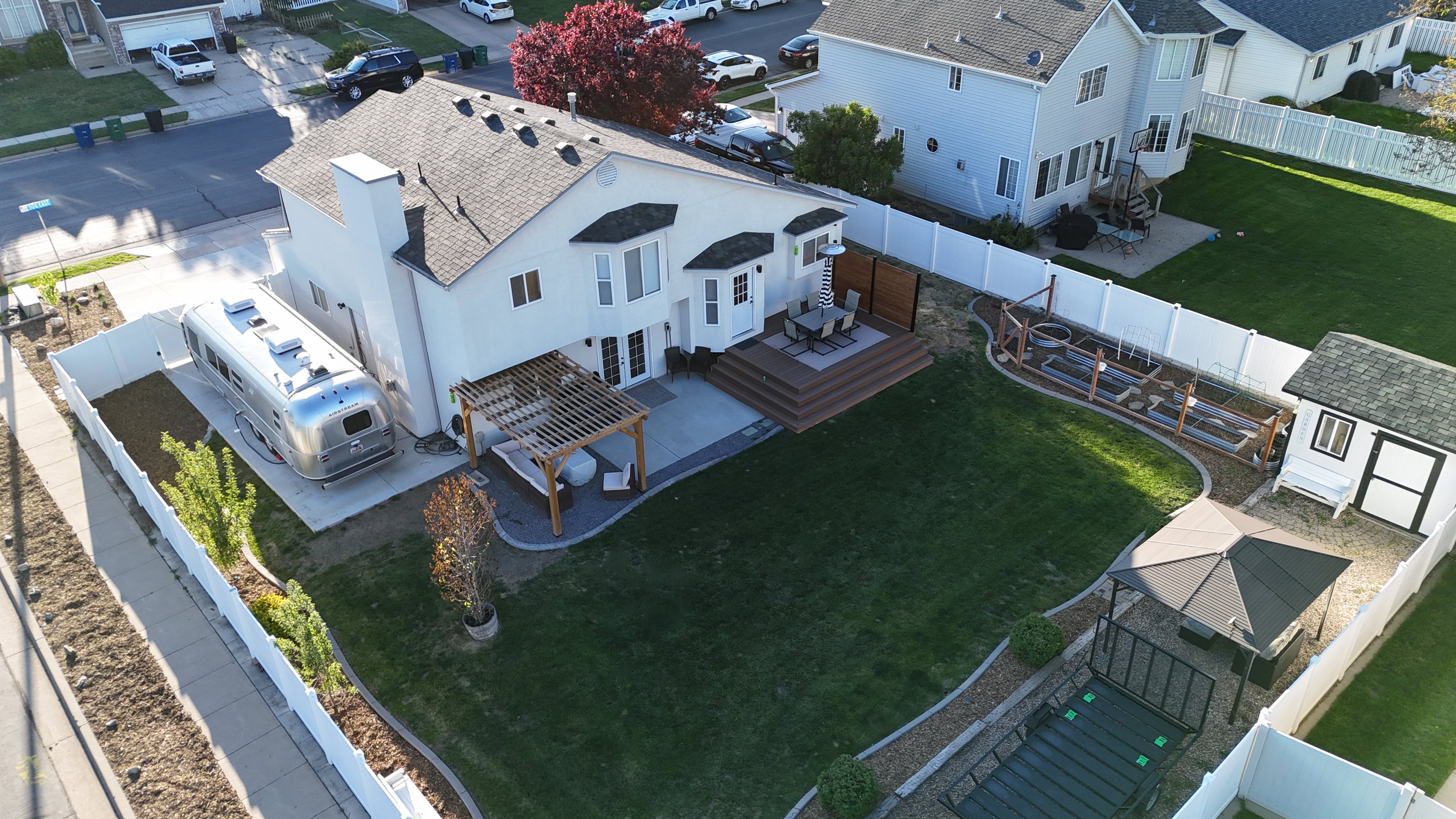 Expansive backyard featuring a large green lawn, multi-level composite deck, and a dedicated storage shed