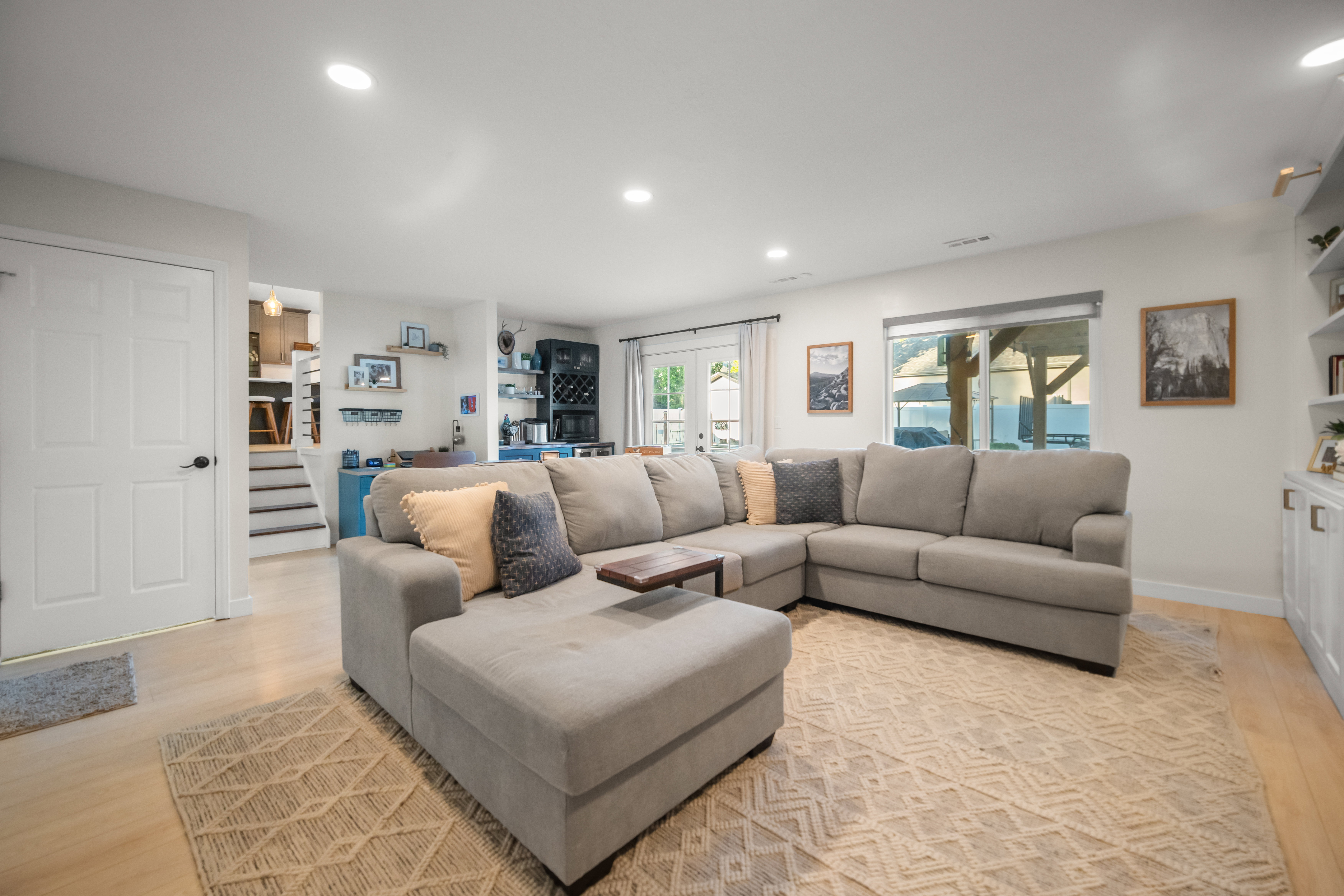 Open-concept living area featuring wood-finish flooring, recessed lighting, white built-in cabinetry with integrated shelving, and a glass sliding door providing access to the exterior