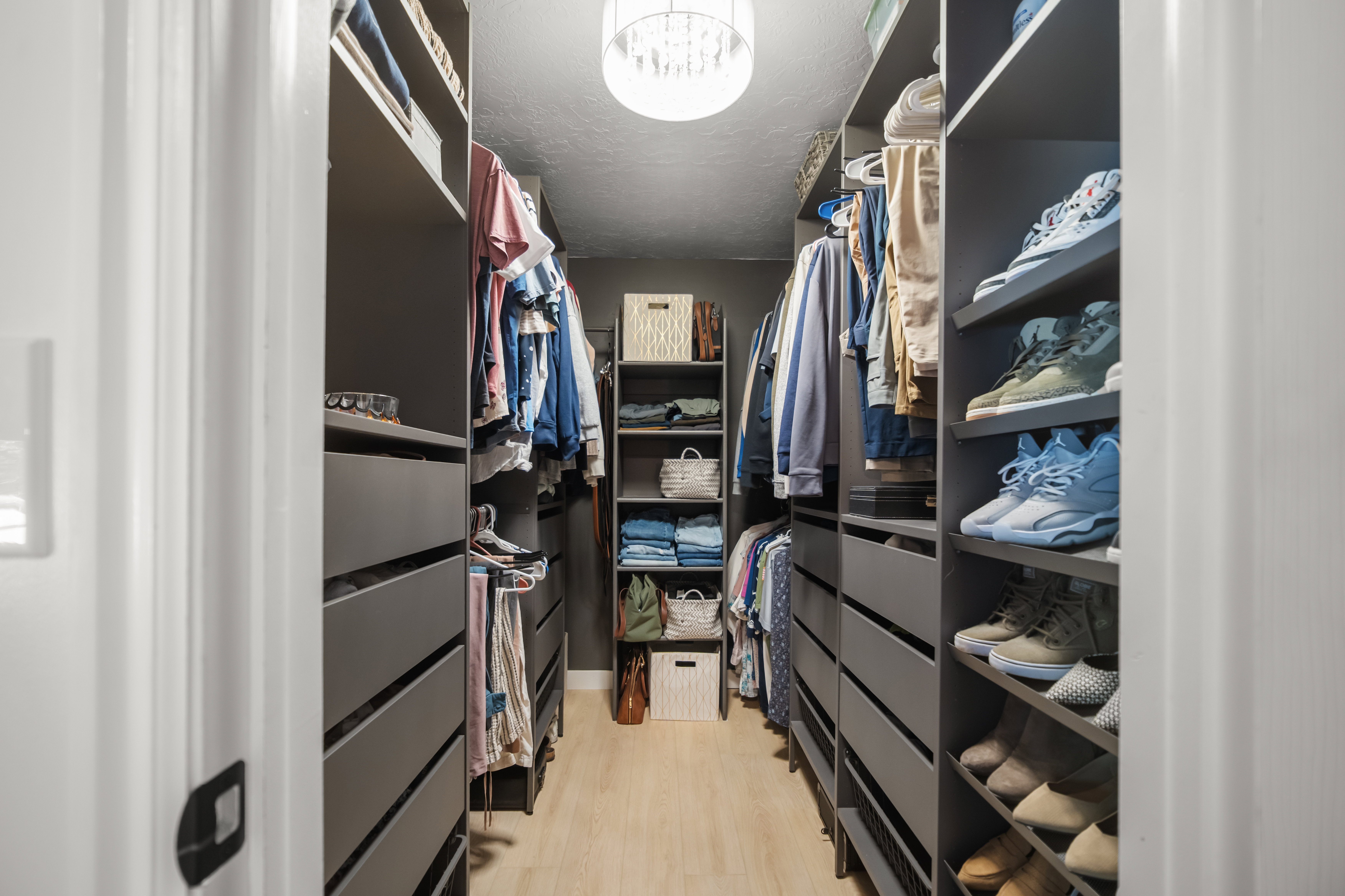 Custom closet system featuring wood-finish flooring, recessed lighting, built-in shelving, and multiple storage drawers