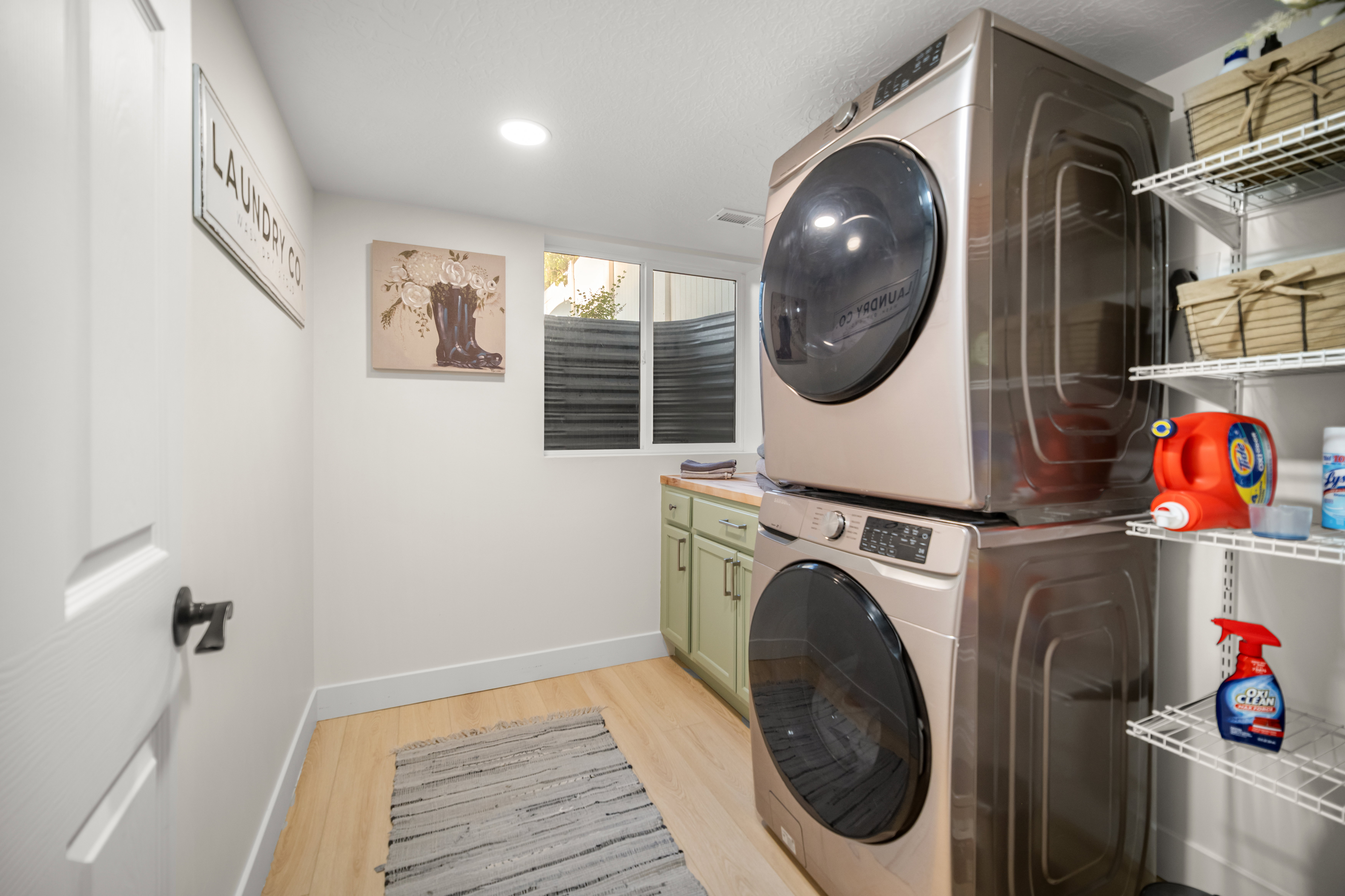 Dedicated laundry area featuring light wood-finish flooring, recessed lighting, and a window for natural illumination