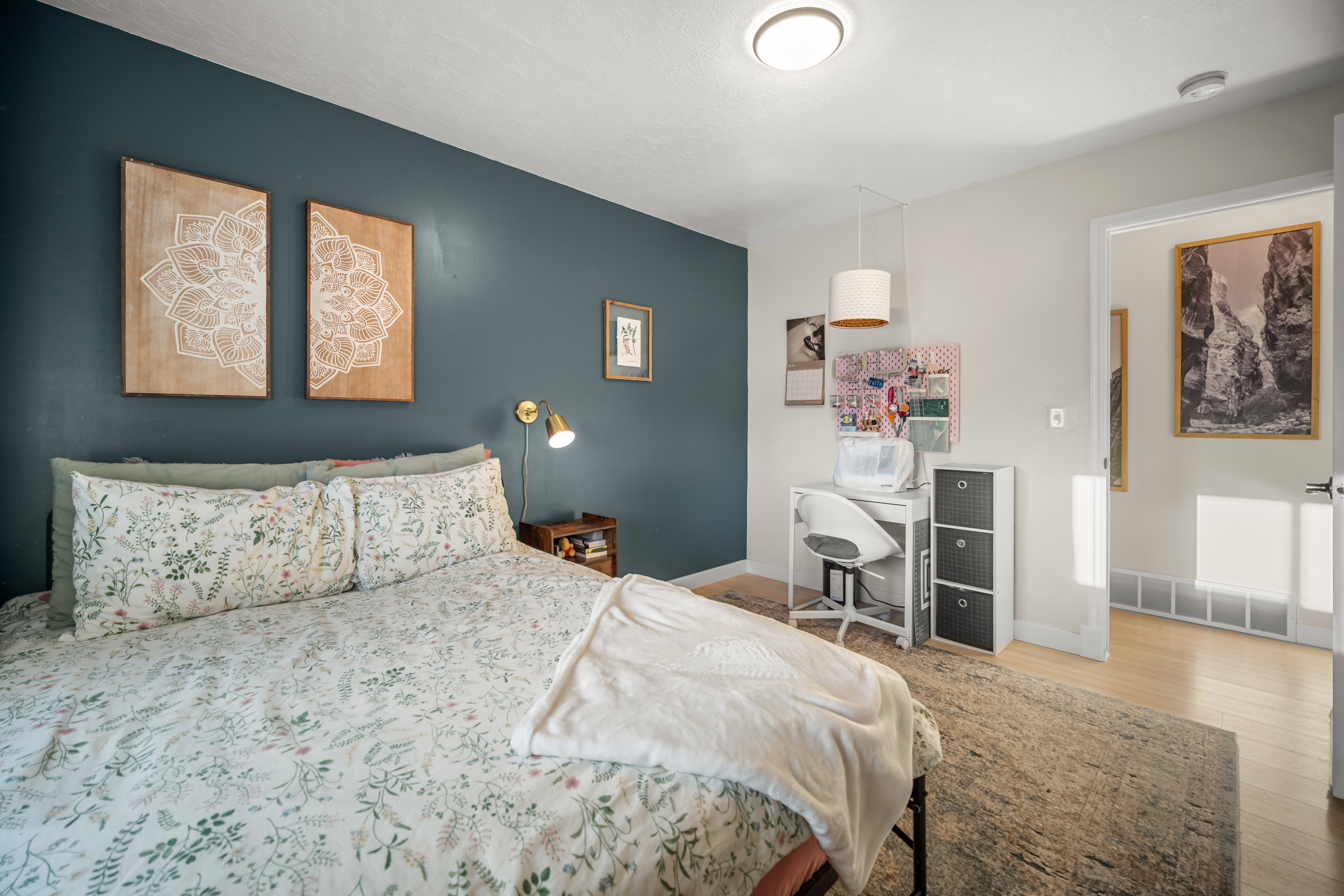 Bedroom featuring a prominent accent wall, flush-mount ceiling light, and light wood-finish flooring
