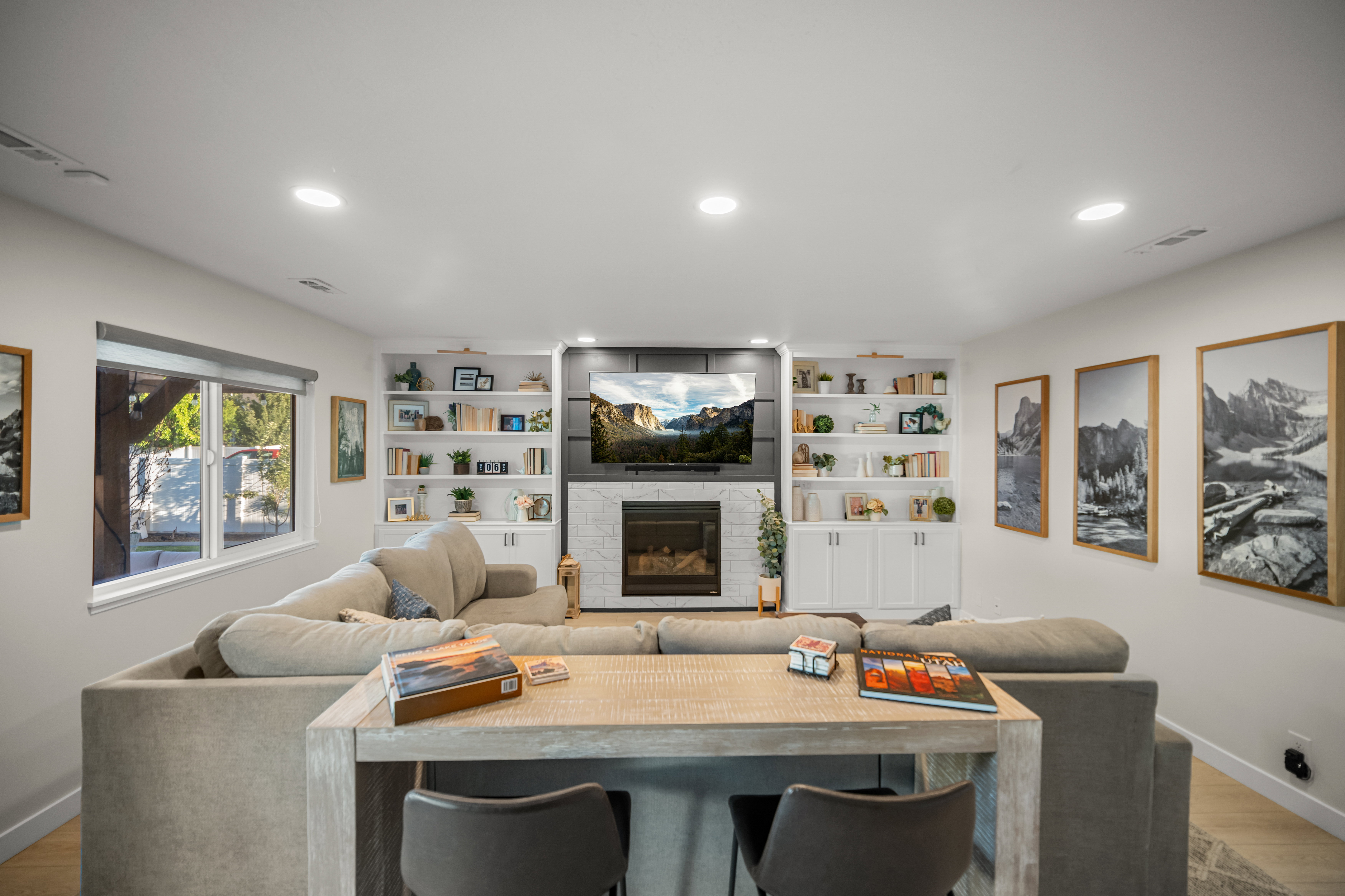 Living area featuring a fireplace with a light-toned surround, built-in shelving, recessed lighting, and wood-finish flooring