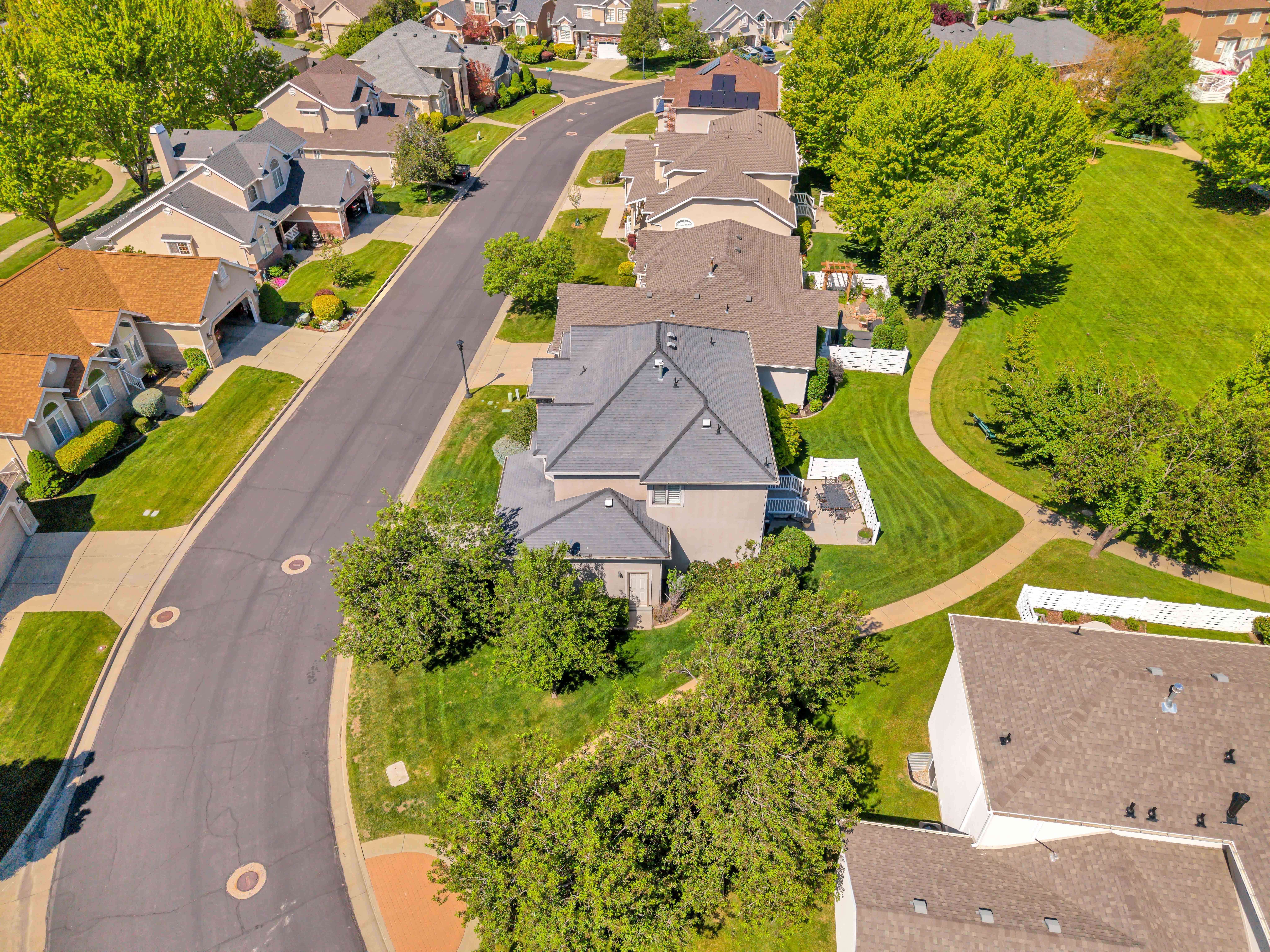 East Side View Residential street with paved sidewalks, manicured lawns, and mature trees