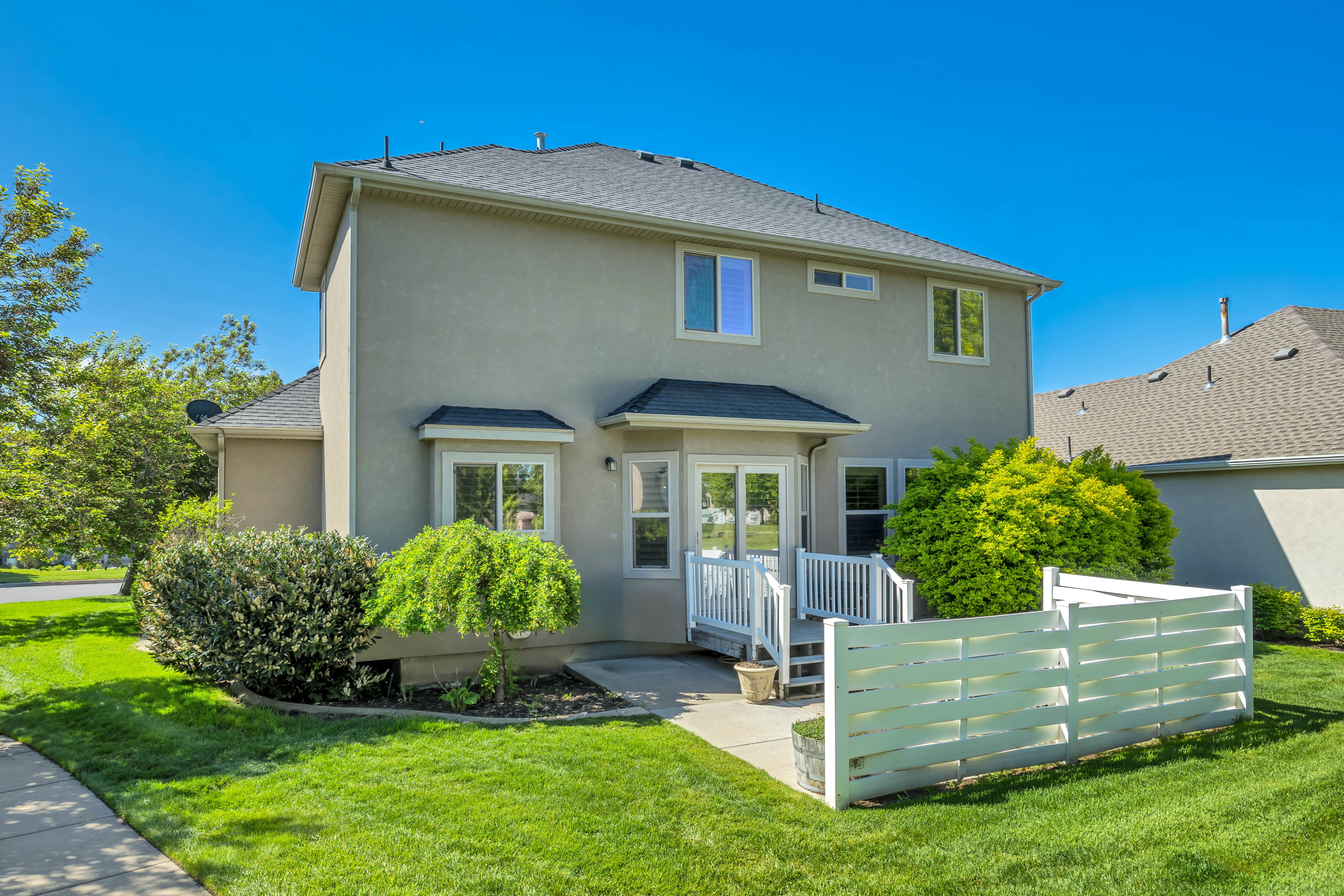 Rear exterior featuring stucco siding, a composition shingle roof, and a white deck with railings