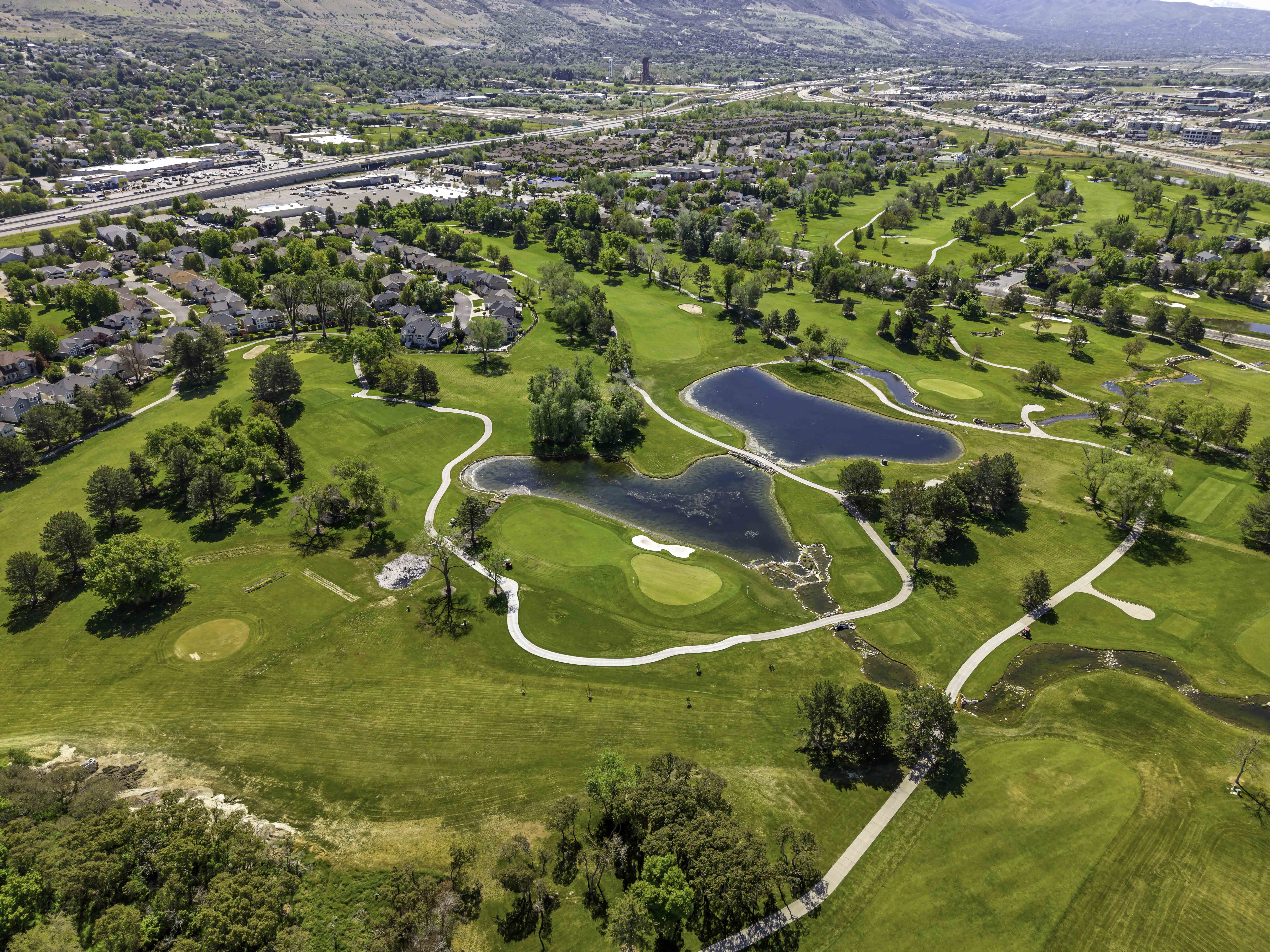 Golf course setting featuring multiple greens, water features, and cart paths