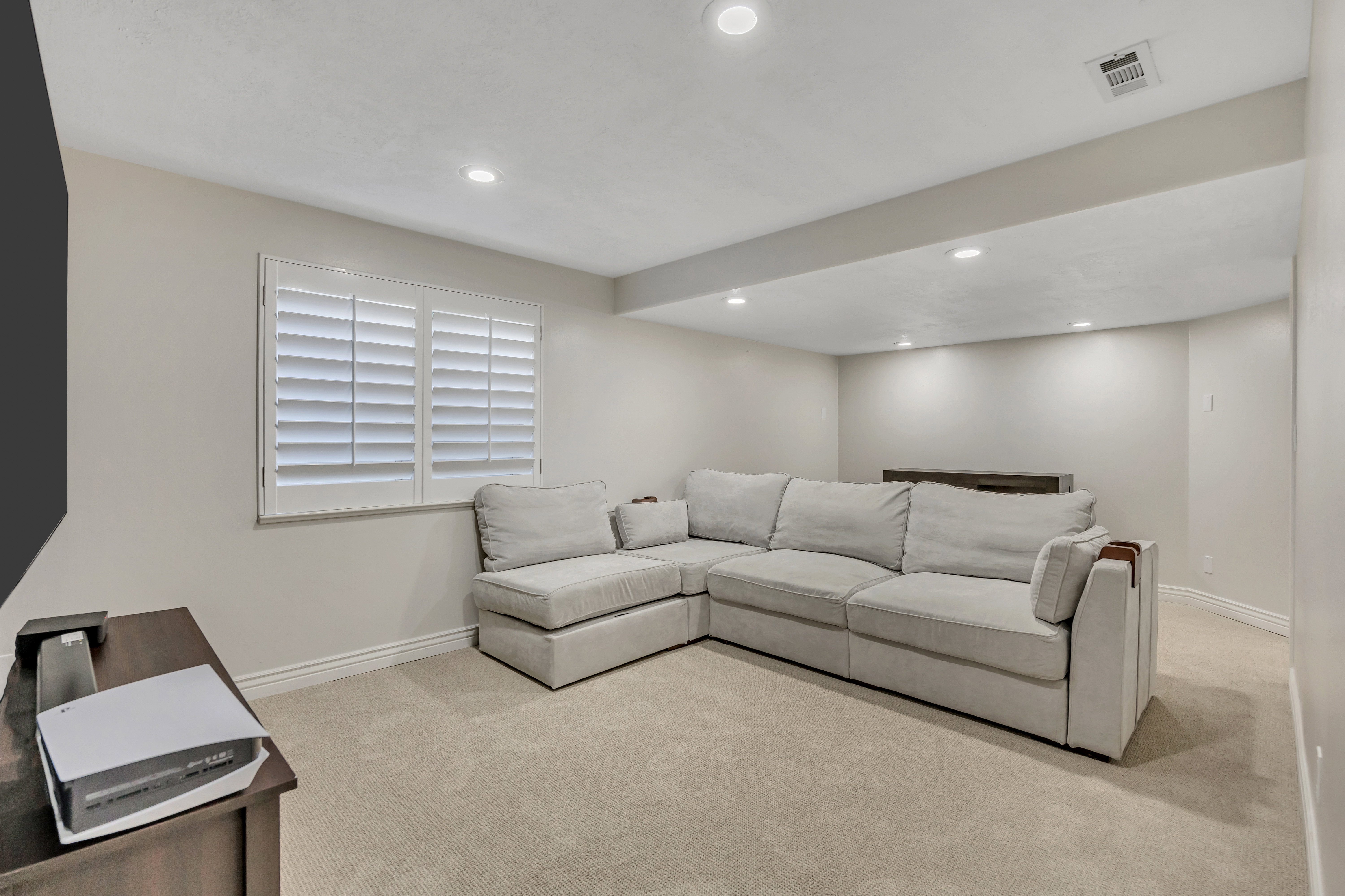 Recessed lighting illuminates this room featuring light-colored carpeting, white baseboards, and neutral wall tones