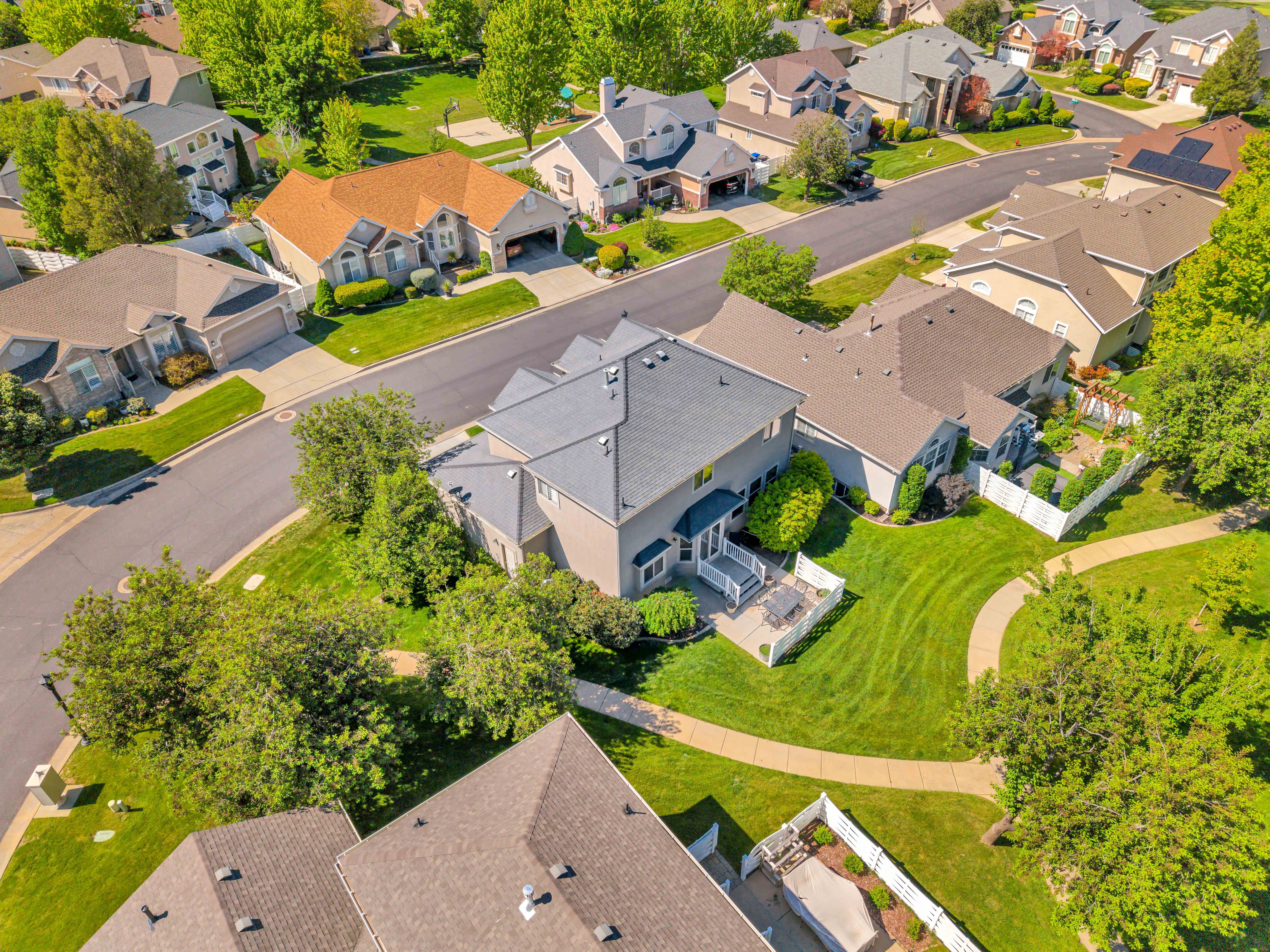 North Side View Aerial perspective showcasing a residential property with a multi-level roofline, a rear deck, and a patio area
