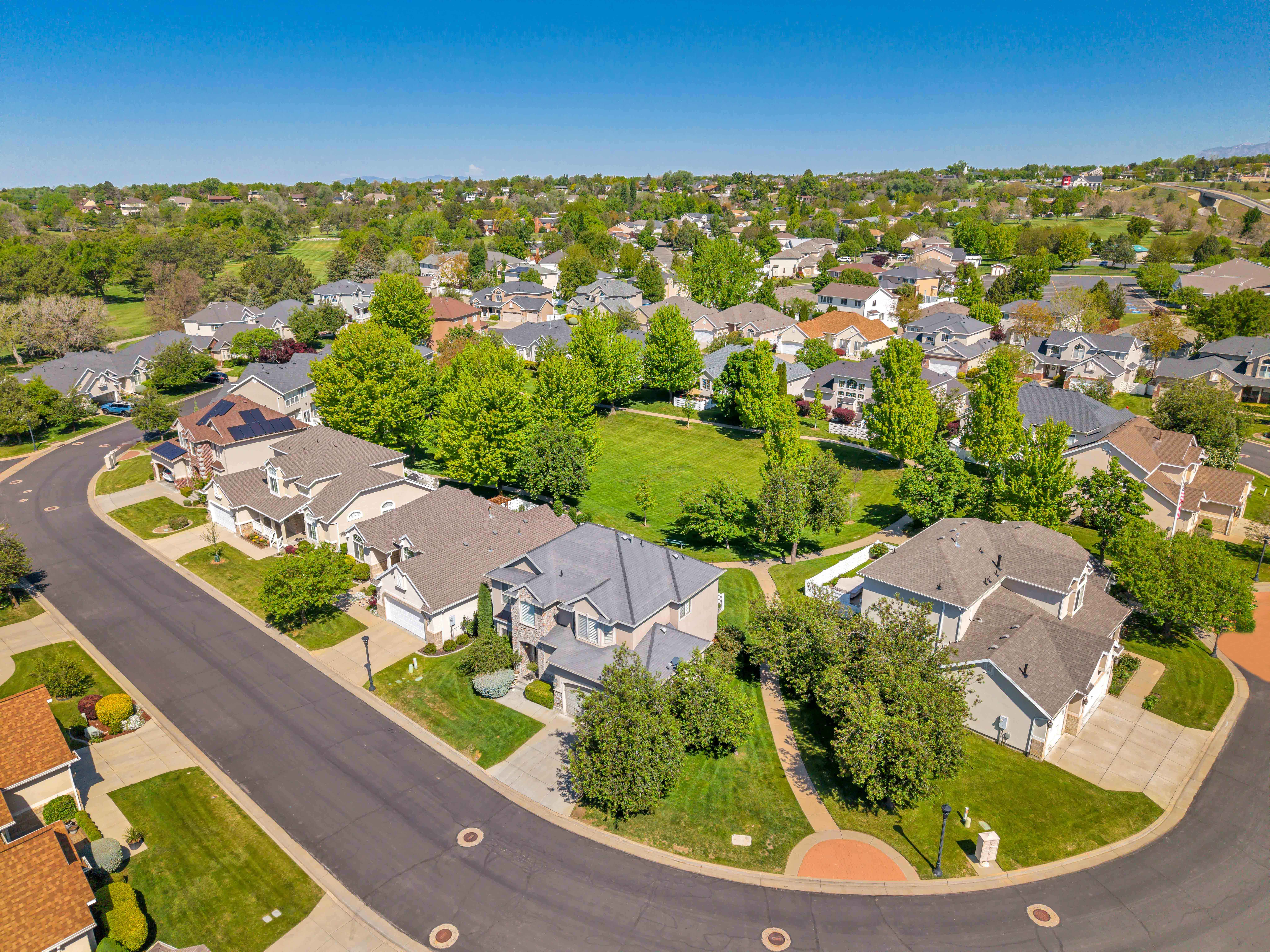 Residential neighborhood featuring a cul-de-sac street, mature trees, and a central green space