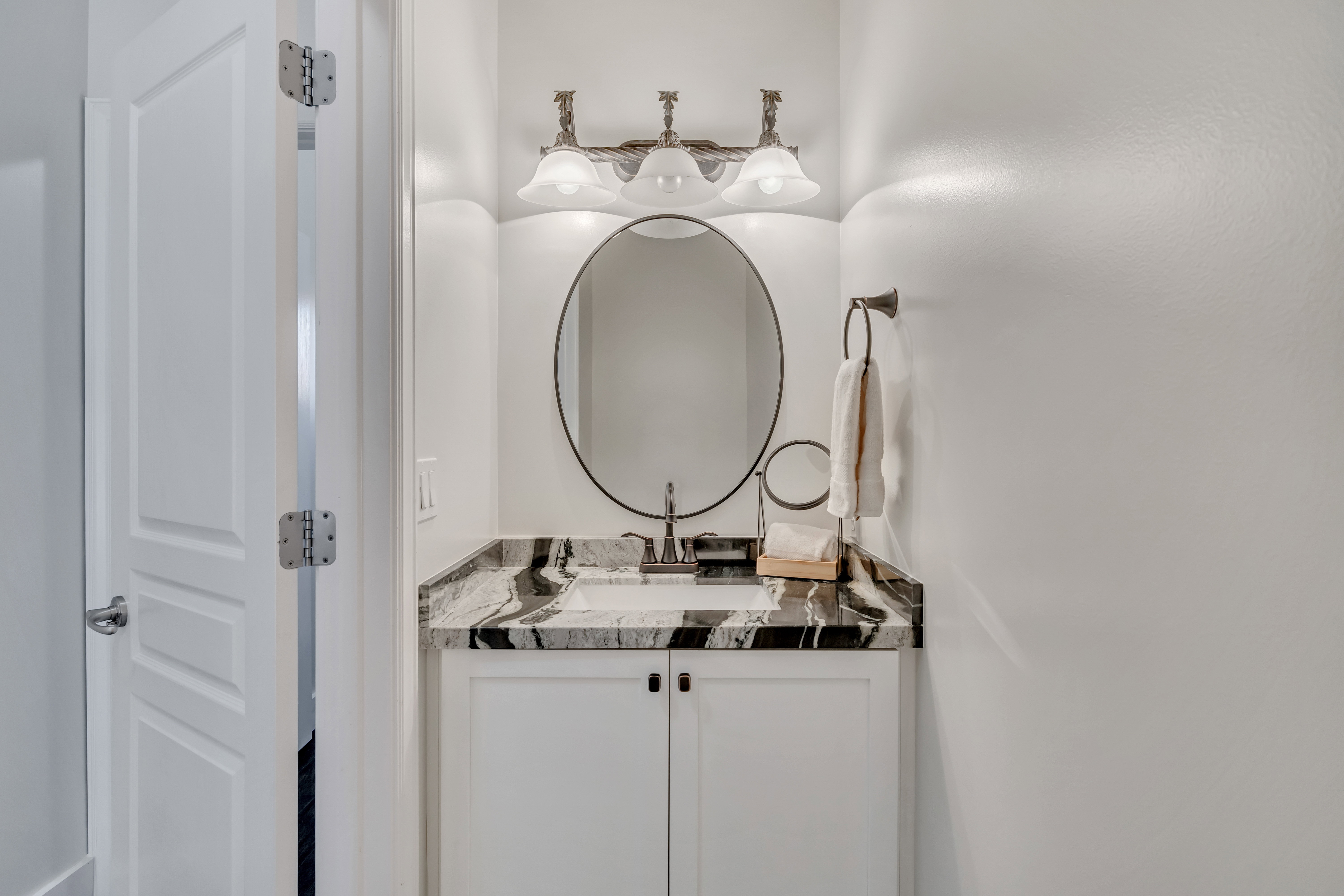 Vanity featuring a black and white patterned countertop, undermount sink, and dark-finished faucet