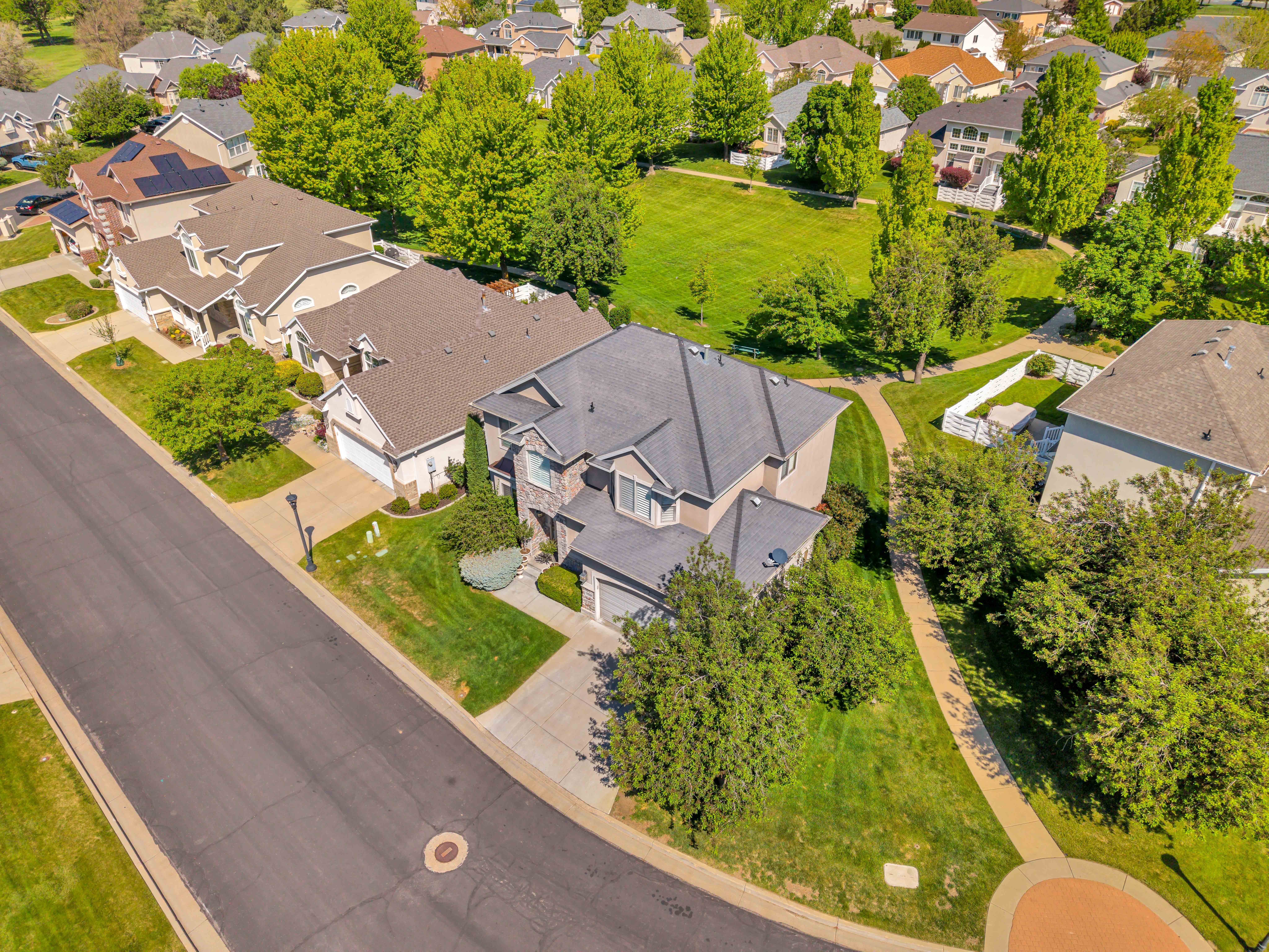 Residential property featuring a paved driveway, attached garage, and manicured landscaping