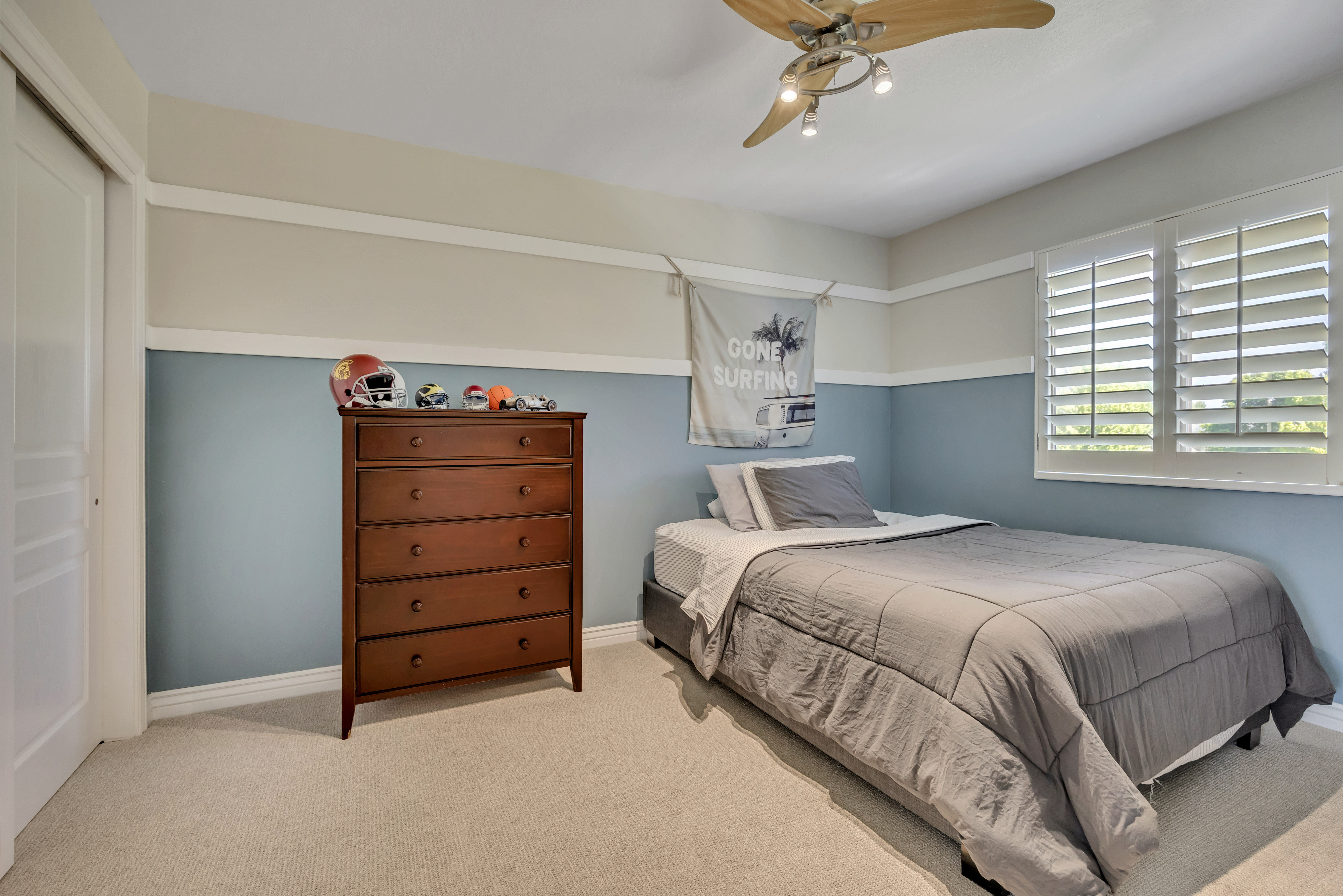 3rd upper level bedroom featuring neutral carpeting, a two-tone painted wall design with white trim, a ceiling fan with integrated lighting, and a window fitted with white plantation shutters