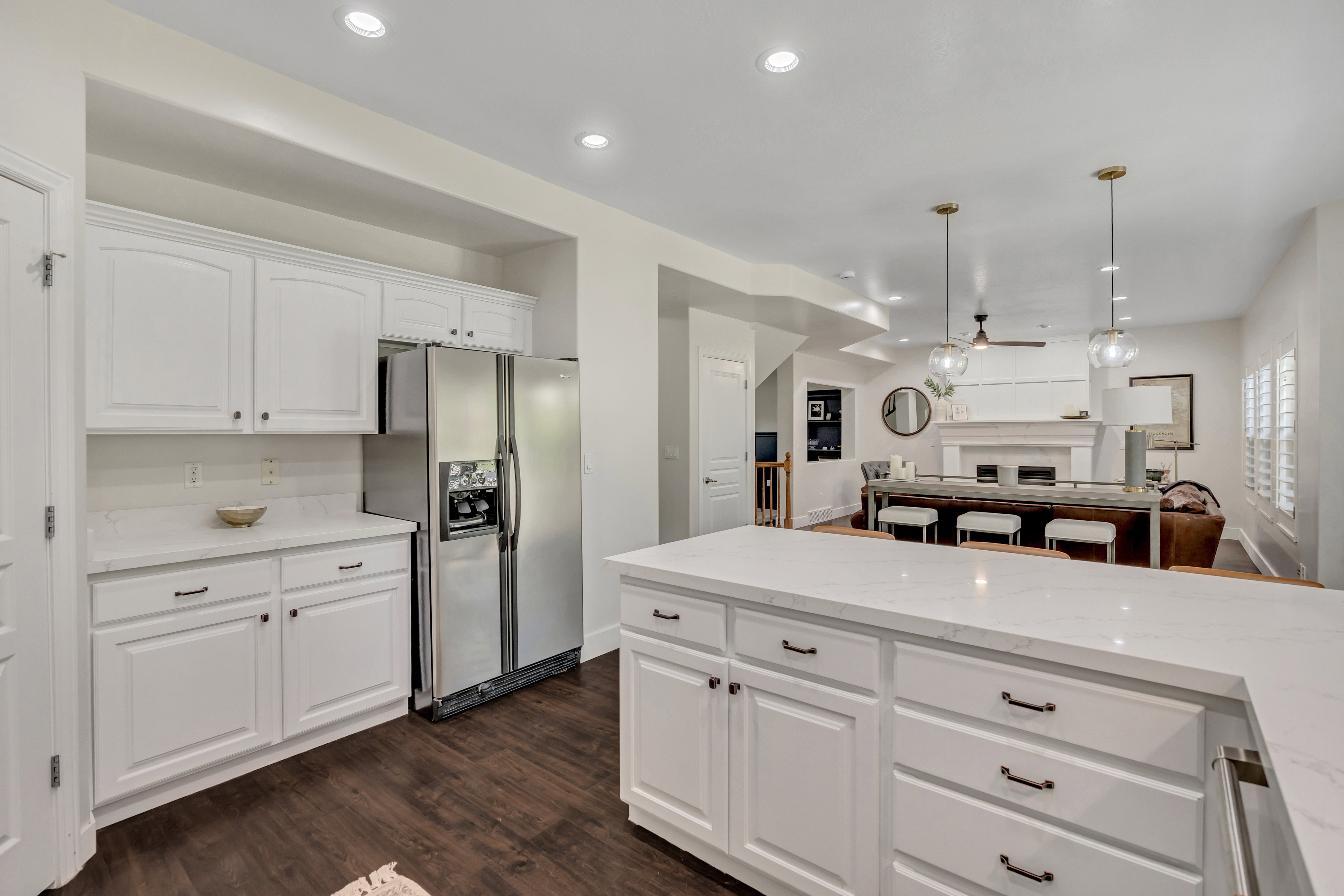Kitchen featuring white cabinetry with quartz countertops with Bronze-finished hardware, a stainless steel refrigerator, and light-toned countertops