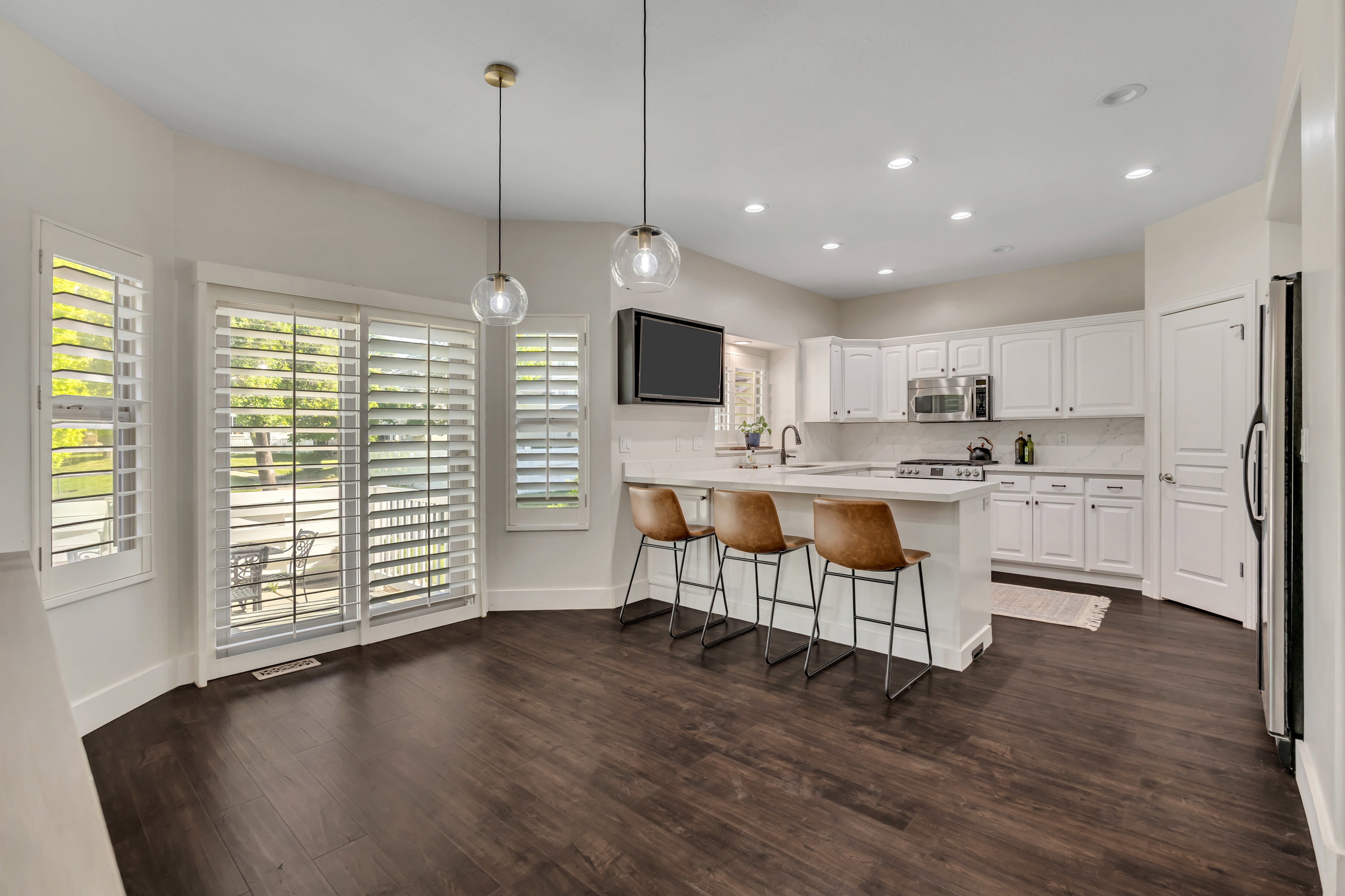 Open Floor Plan Kitchen with large pantry featuring stainless steel GE Cafe Appliances with bar seating, white shaker cabinetry, stainless steel appliances, and a tile backsplash
