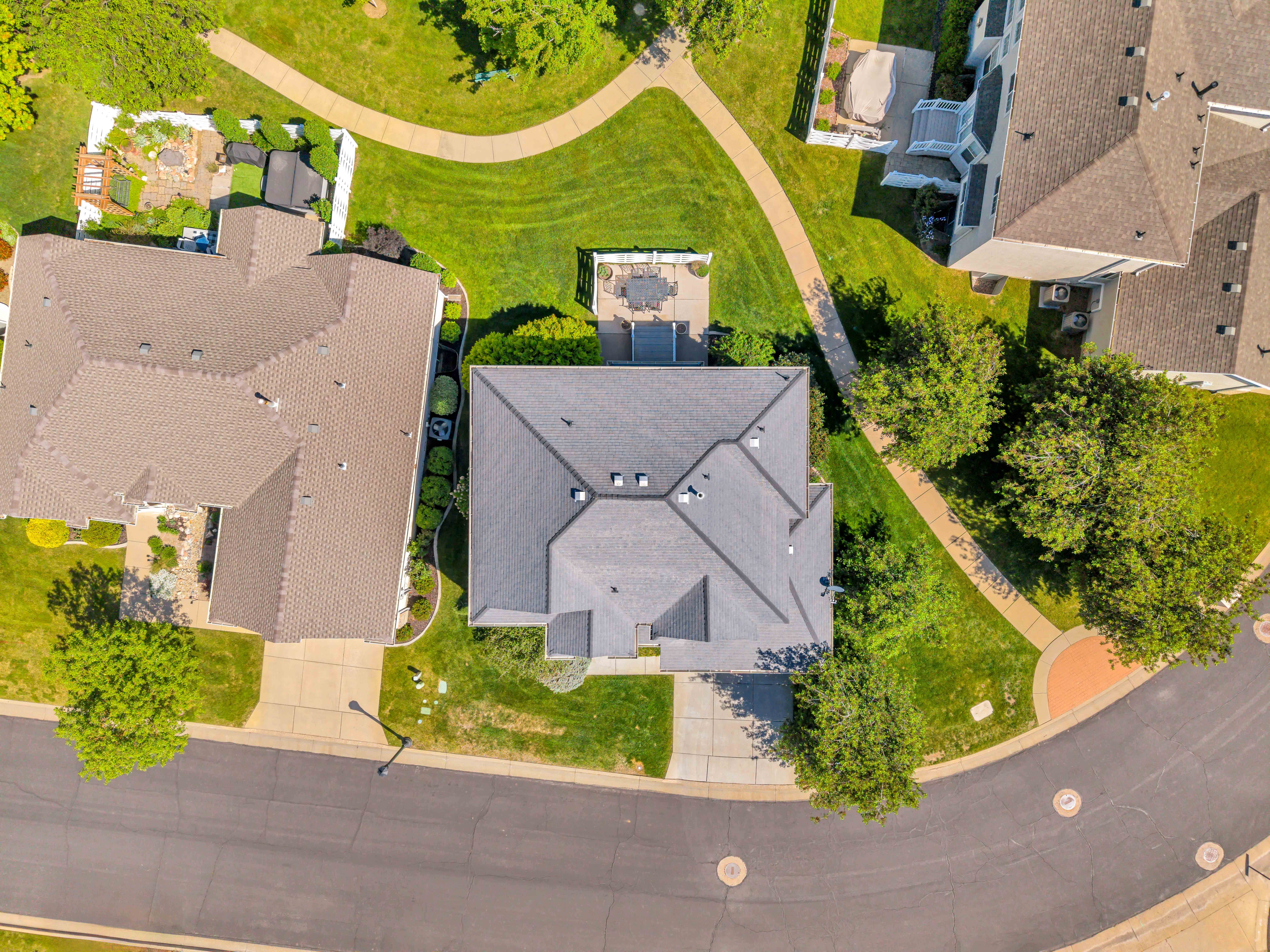 South Facing View Expansive property featuring a grey shingle roof, mature trees, and a concrete driveway