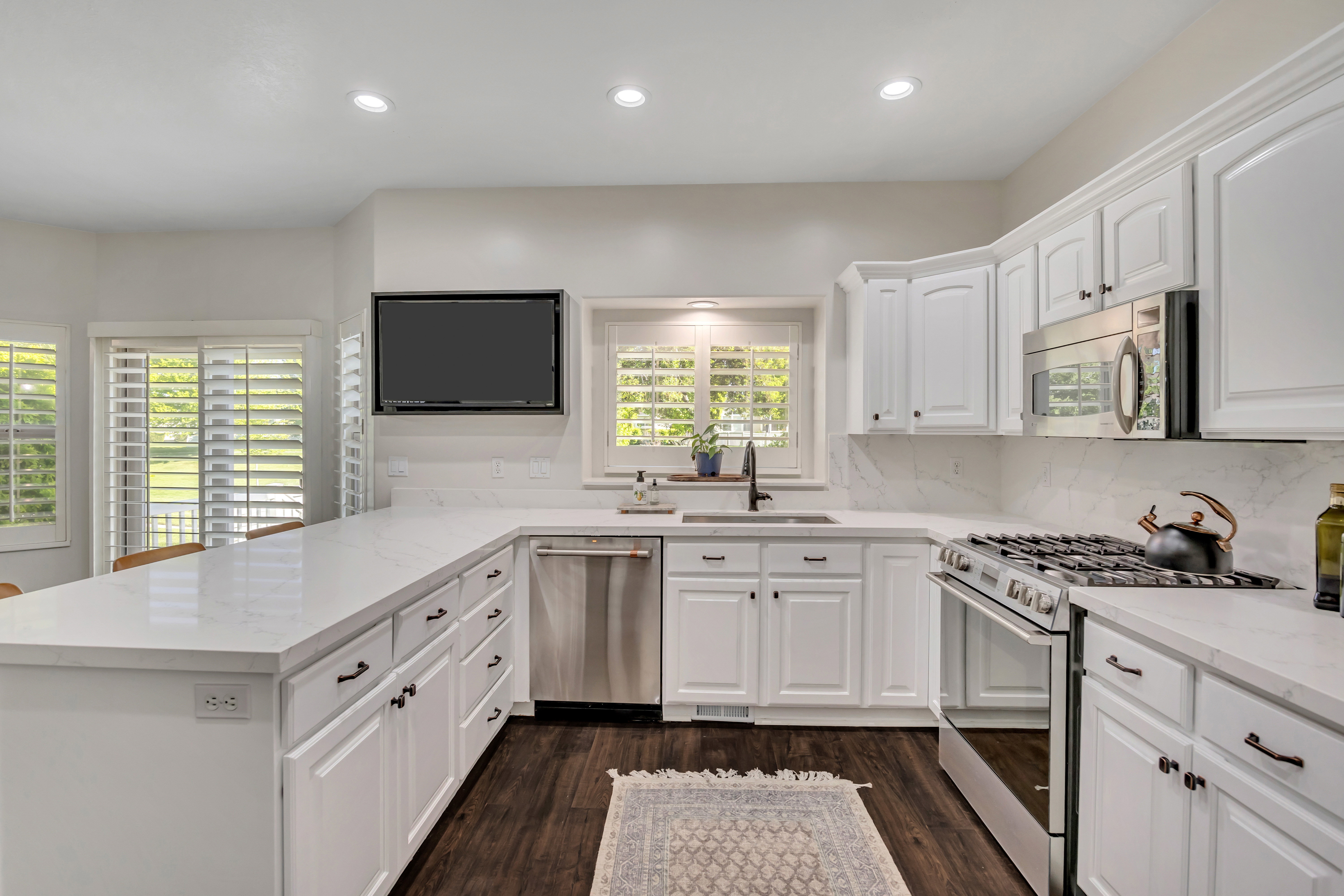 Kitchen featuring white cabinetry, quartz countertops, stainless steel appliances, and dark wood flooring