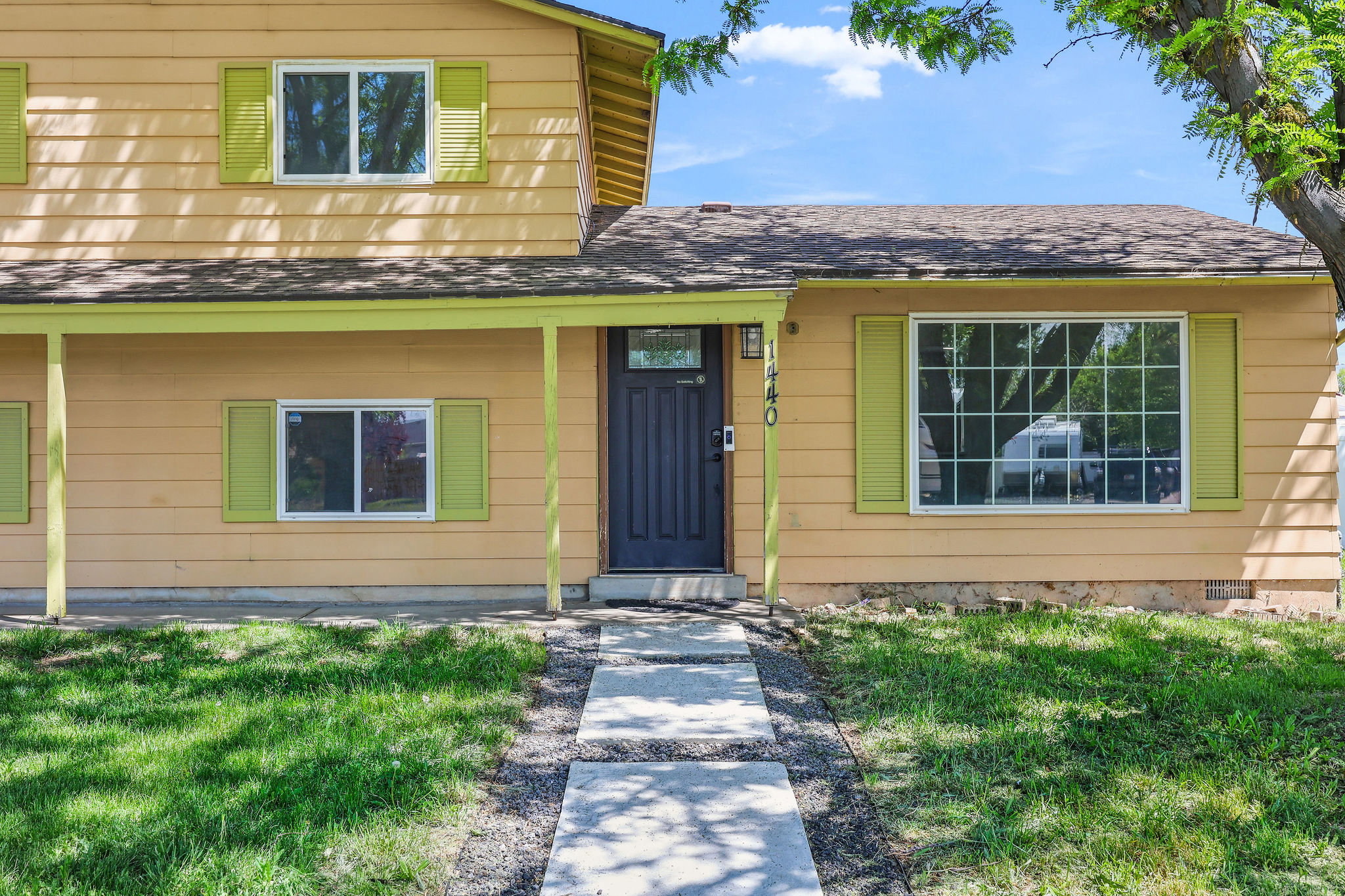 Two-story residence featuring a covered front porch with yellow trim, a dark paneled entry door, and lime green window shutters