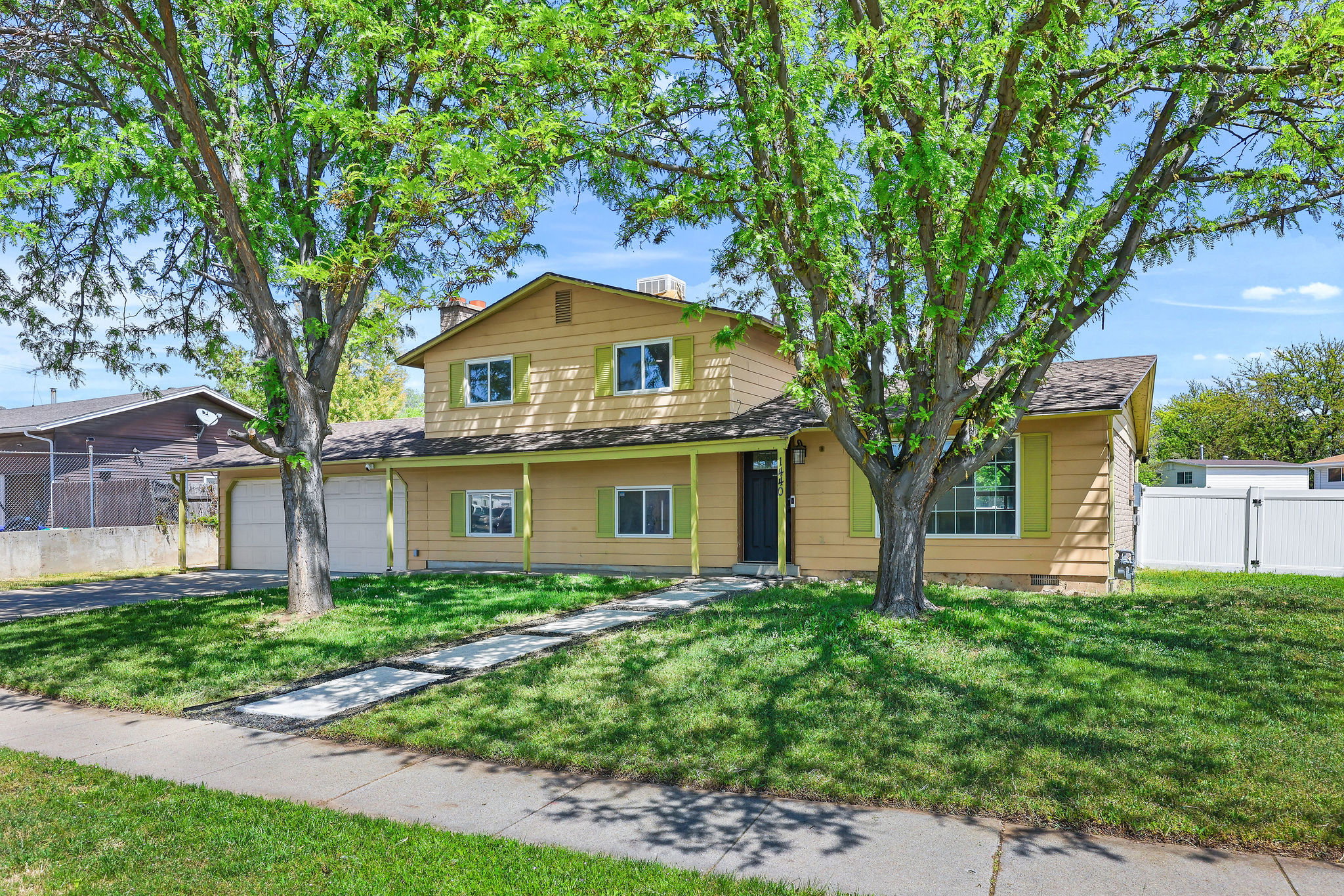 Two-story residence featuring a covered front porch, a dual garage, and a manicured lawn