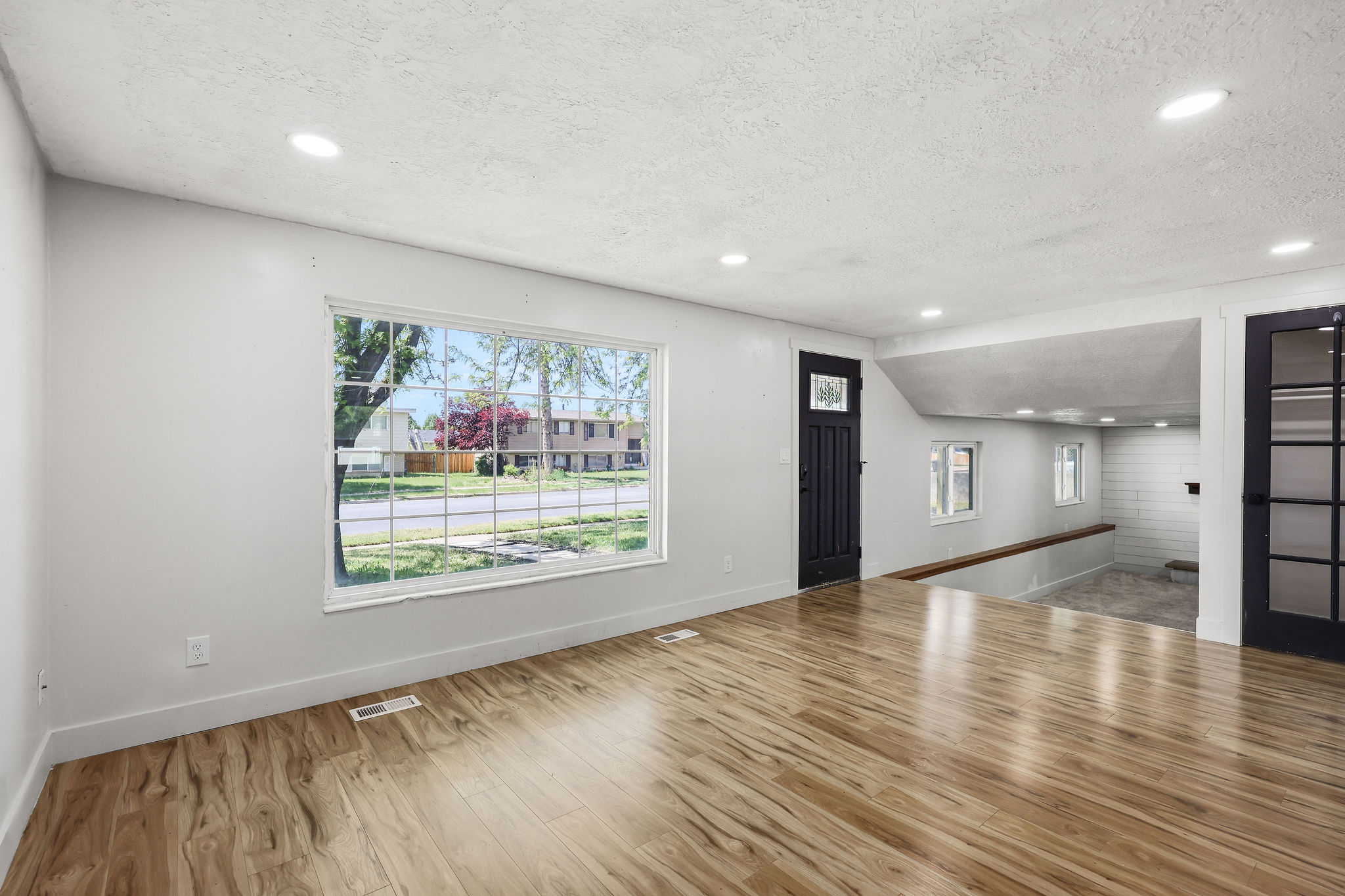 Spacious room featuring wood-finish flooring, white walls, and recessed lighting