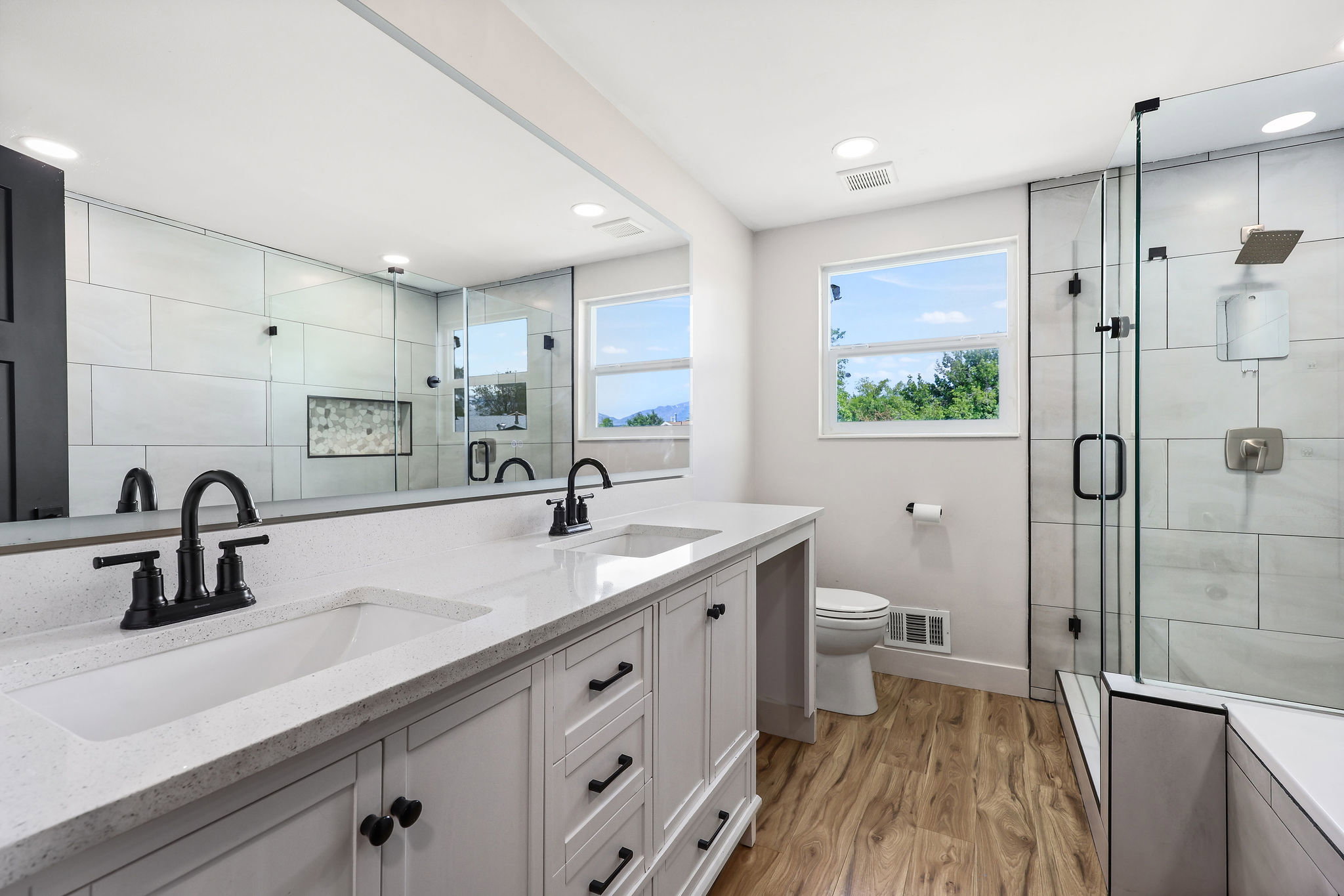 Dual vanity with white cabinetry, matte black fixtures, and light-toned countertops