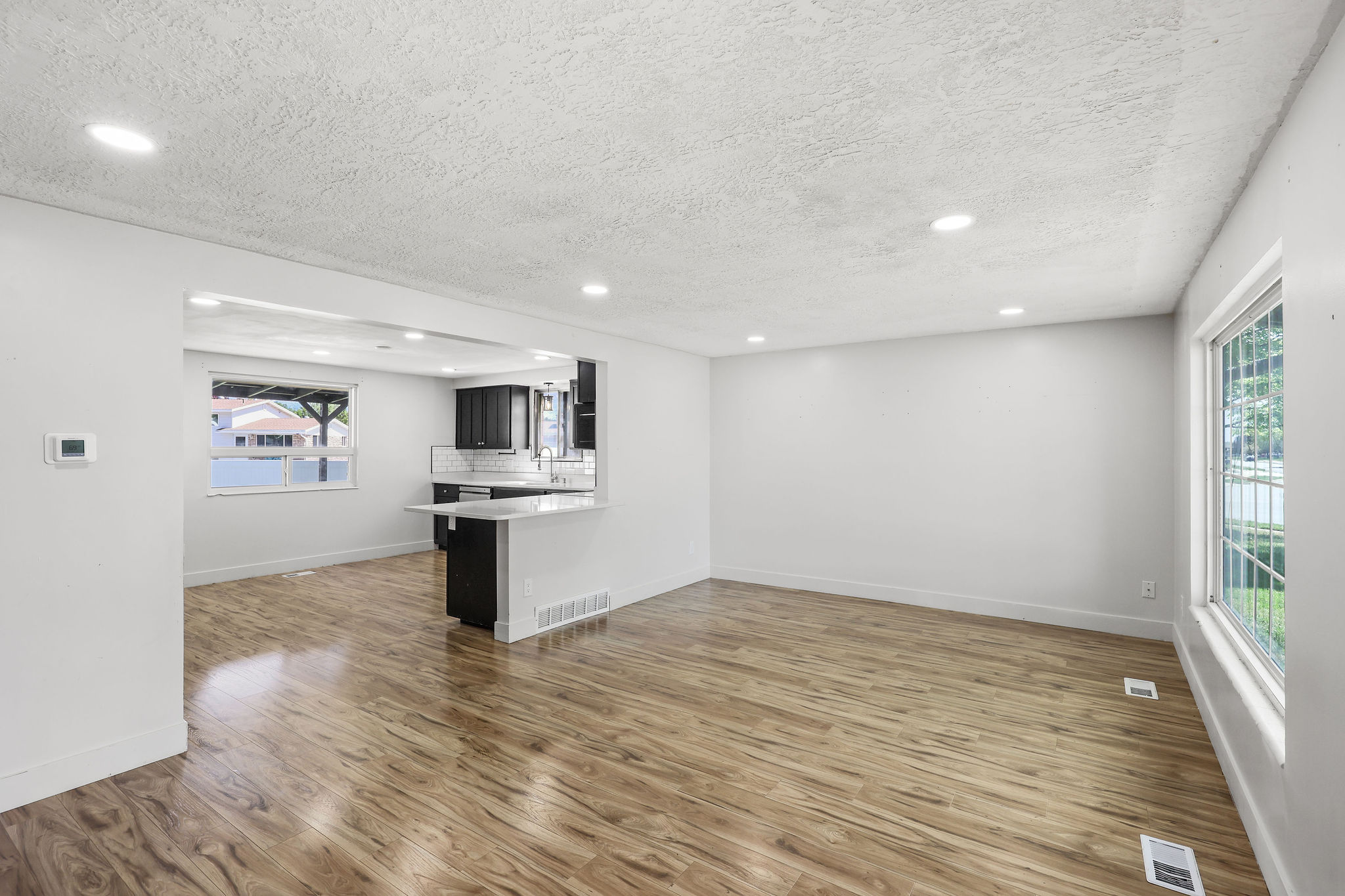 Open-concept living area featuring wood-finish flooring, recessed lighting, and a white color palette