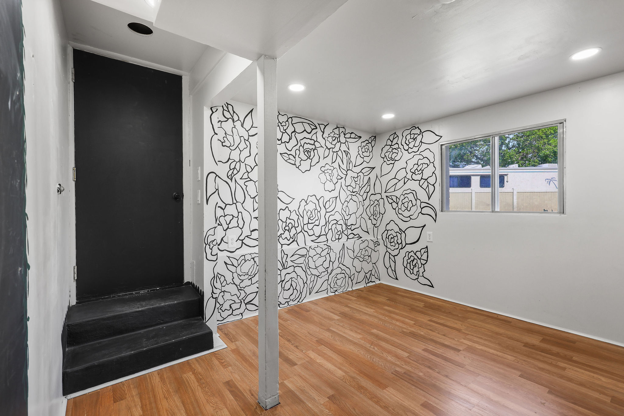 Room featuring wood-finish flooring, a decorative wall mural, and recessed lighting