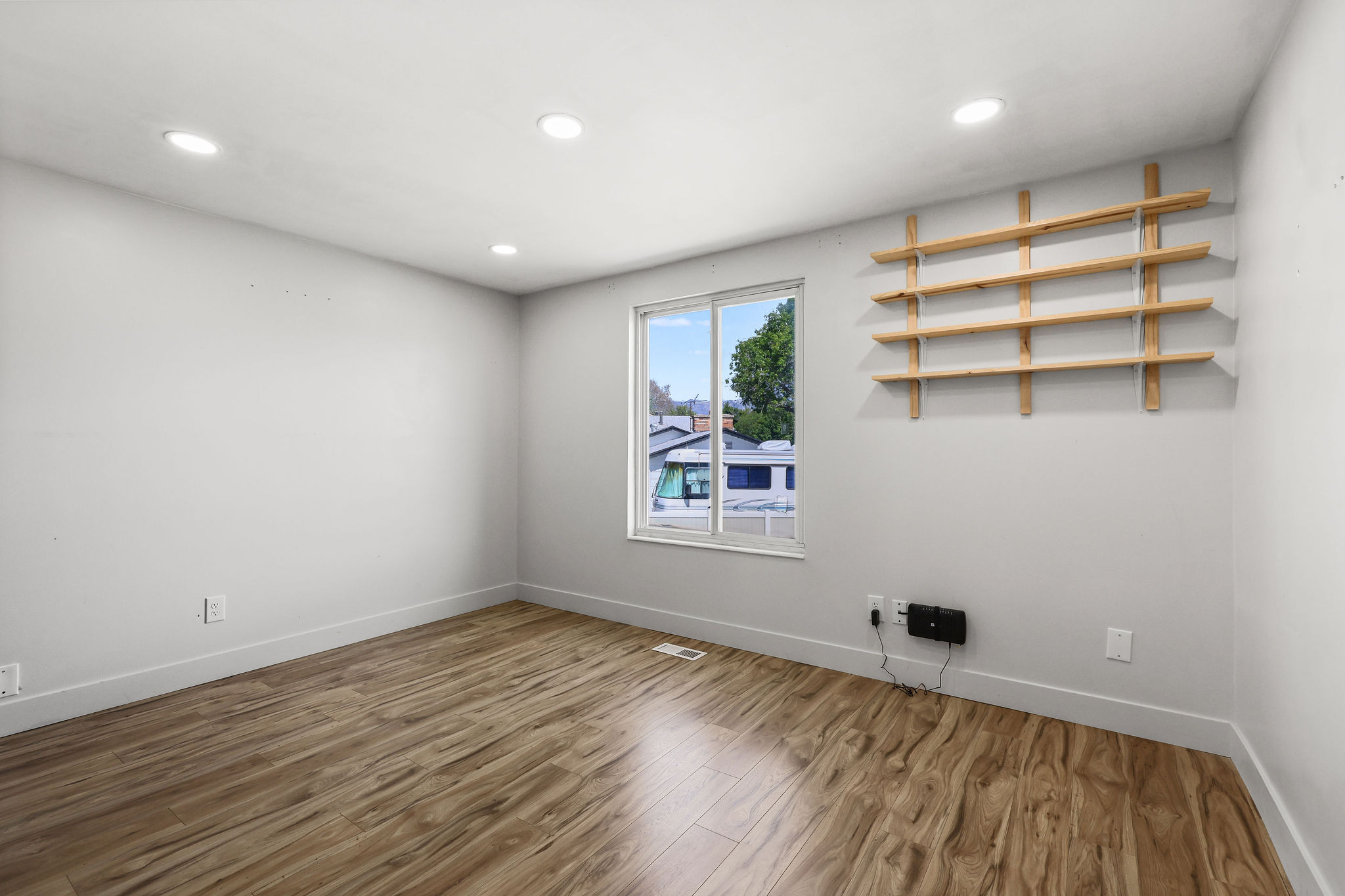 Room featuring wood-finish flooring, recessed lighting, and a window with a white frame