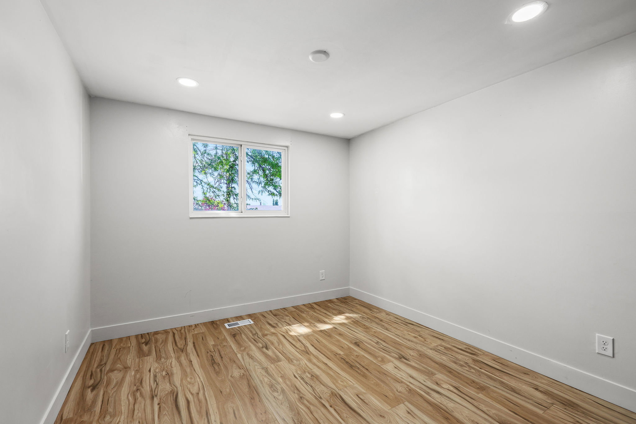 Room featuring wood-finish flooring, recessed lighting, and a window with white trim