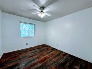 Interior room with textured wood-finish flooring, white walls, and a white ceiling fan with integrated lighting