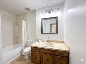 Bathroom featuring a wood-finish vanity with a built-in sink and countertop, a framed wall mirror, a three-light vanity fixture, and a full-size bathtub with tiled walls