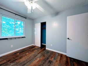 Room featuring wood-finish flooring, a window with a white frame, and a ceiling fan