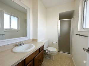 Bathroom featuring an integrated sink vanity with wood-finish cabinetry, a framed mirror, a privacy glass shower enclosure, and light-toned floor tiling