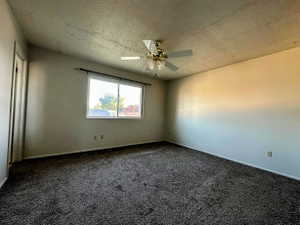 Spacious room featuring neutral wall tones and dark gray carpeting