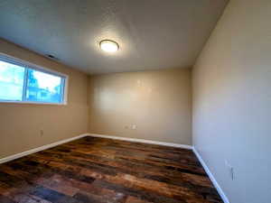 Room featuring wood-finish flooring, a rectangular window with white trim, a flush-mount ceiling light fixture, and light beige wall paint