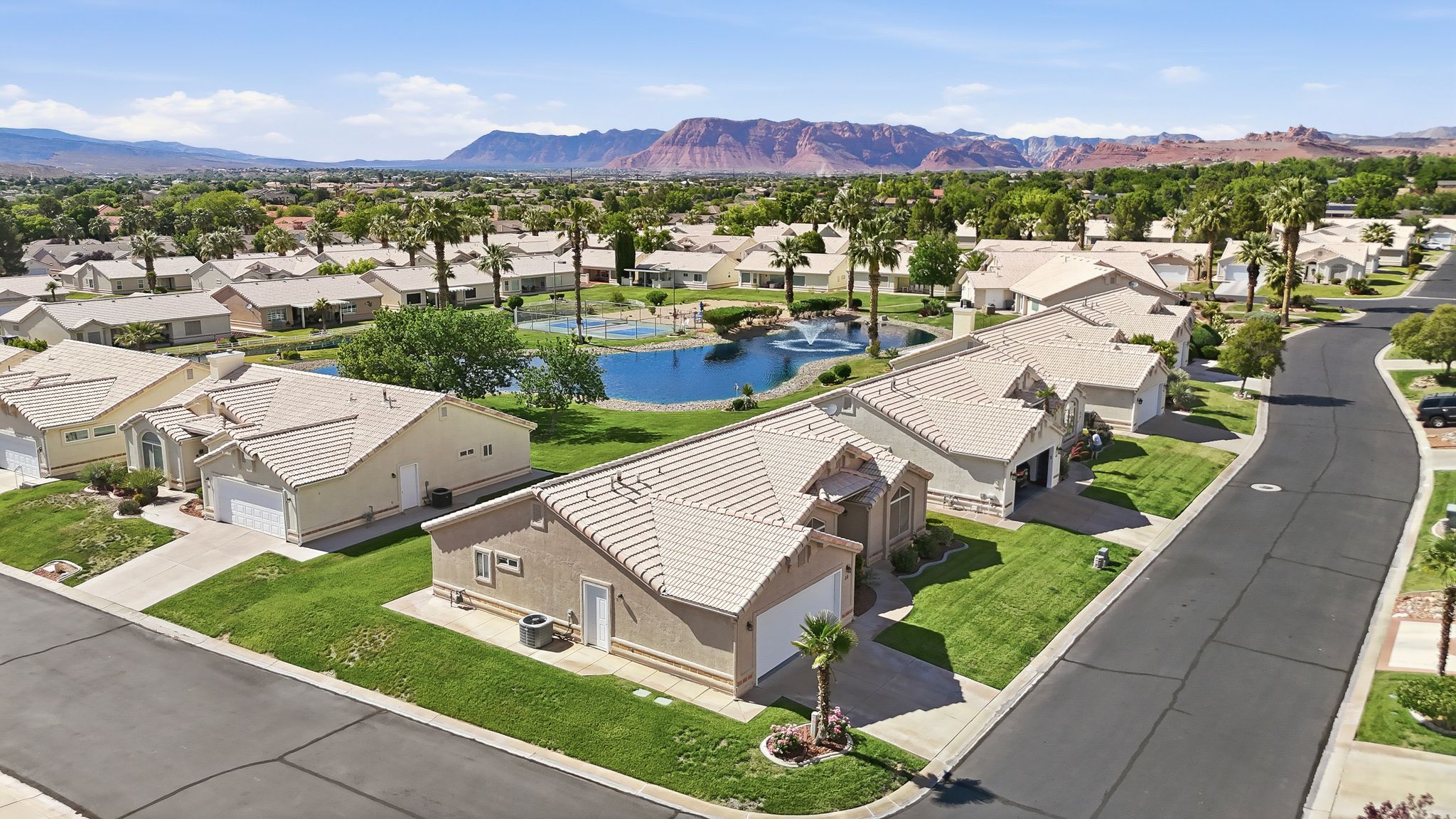 Aerial perspective of a residential neighborhood featuring single-story homes with light-colored tile roofs and manicured lawns