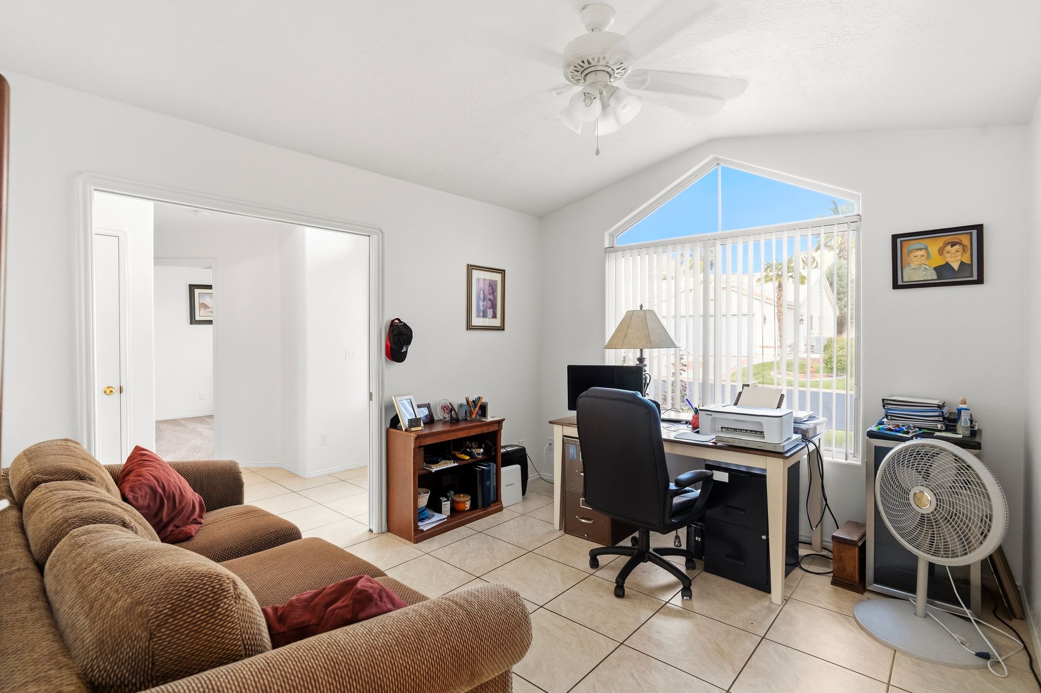 Vaulted ceiling with an architectural window, ceiling fan, and tile flooring