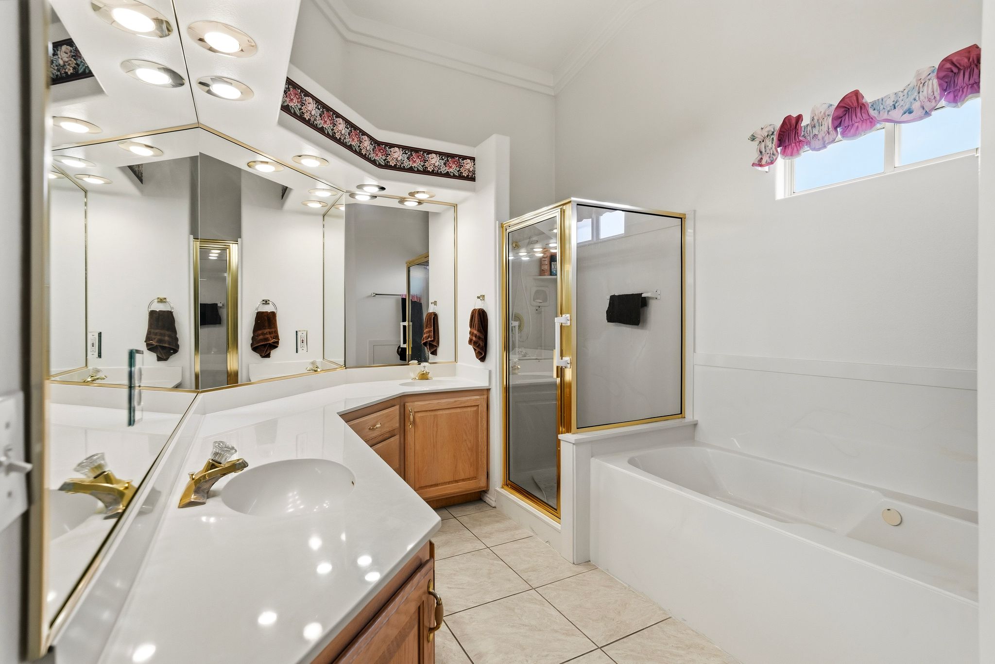 Bathroom featuring a dual vanity with light-toned countertops, integrated sinks, and brass-finish fixtures