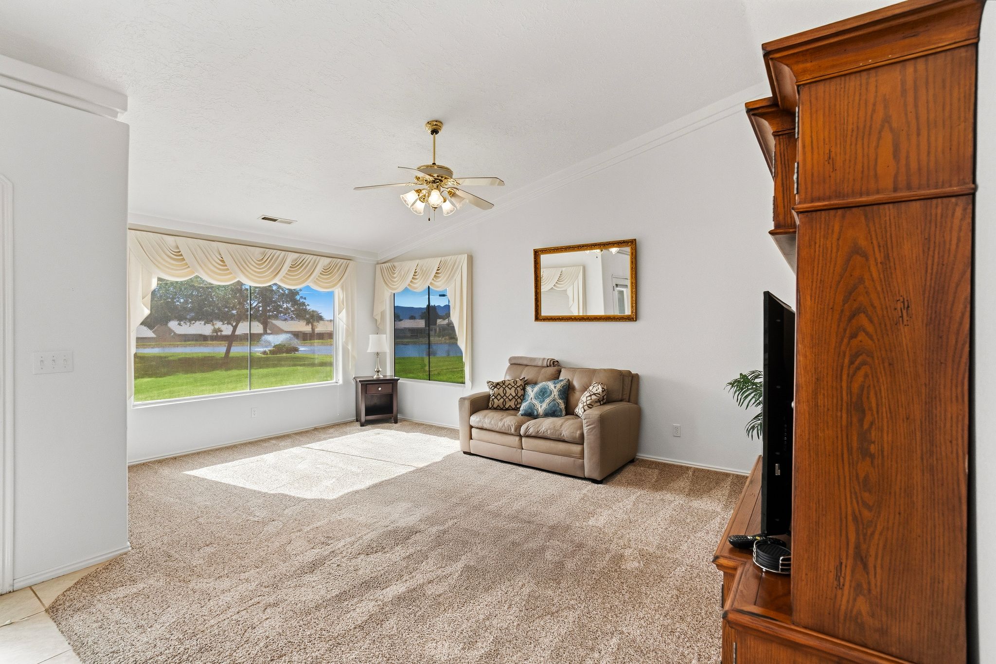 Spacious living area featuring expansive windows, neutral tone carpeting, and a built-in media cabinet