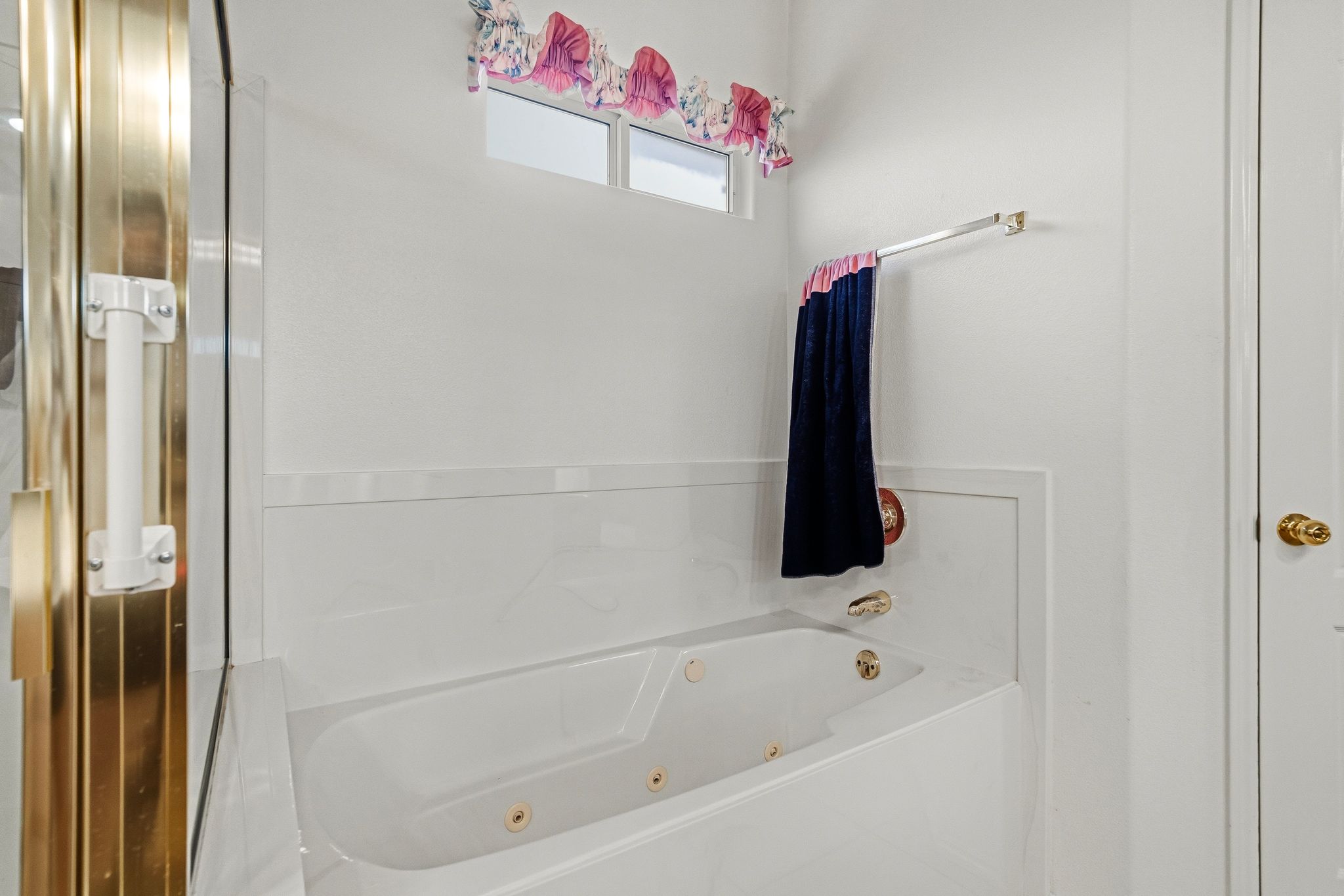 Jetted soaking tub with a white surround and gold-tone fixtures