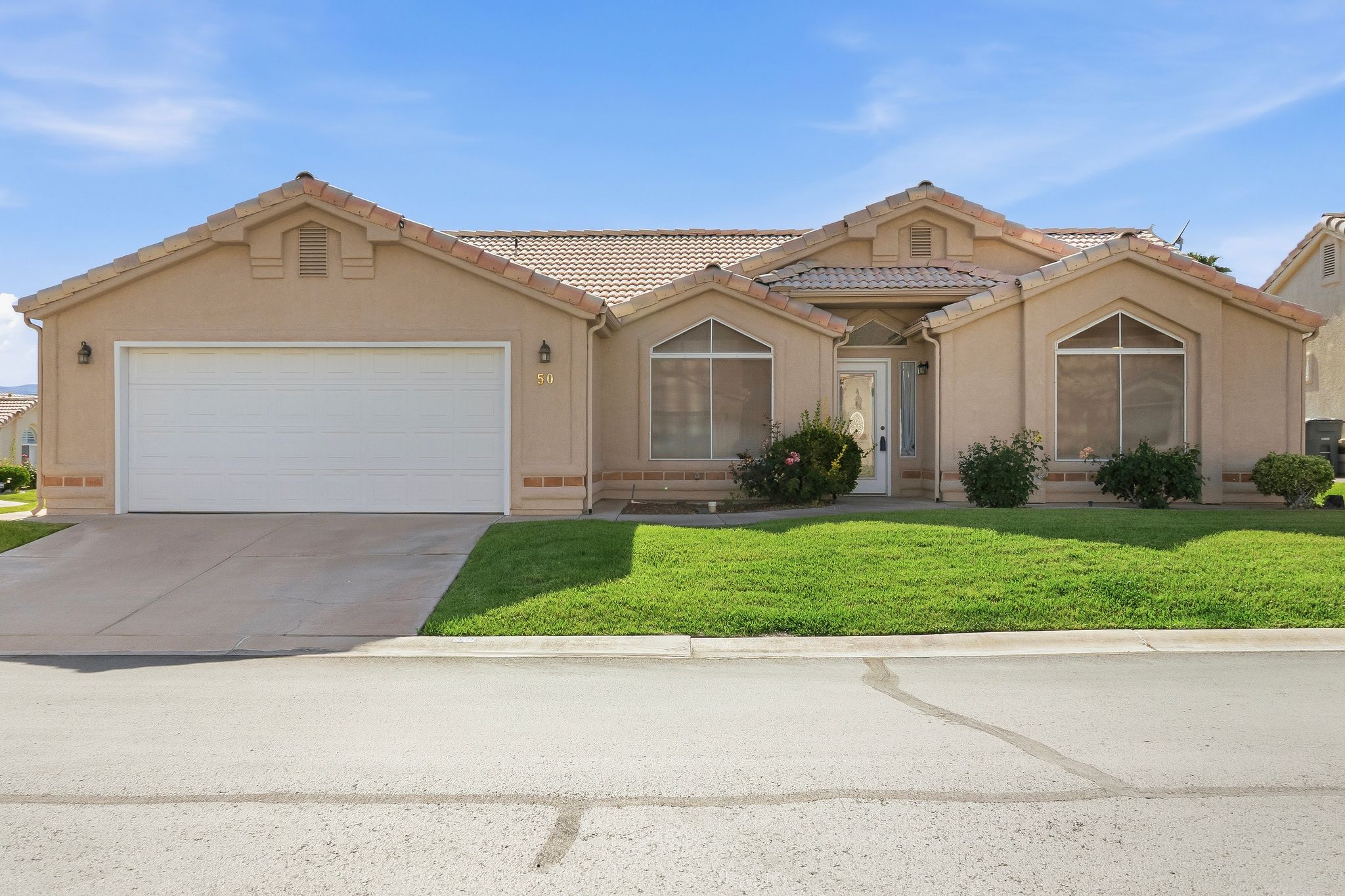 Stucco-finish residence with a tile roof, an integrated two-car garage, and a concrete driveway