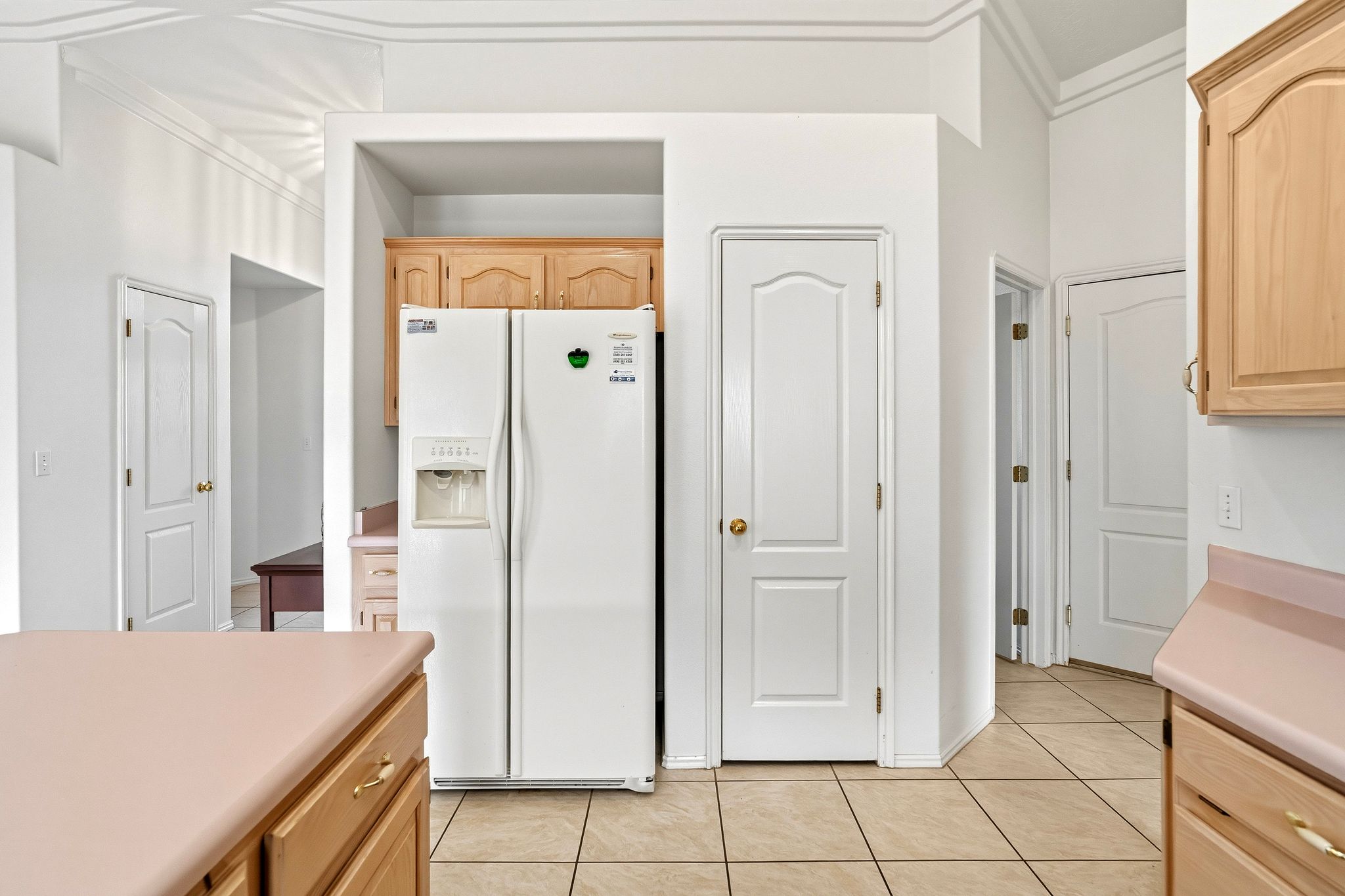 Kitchen space featuring light wood-finish cabinetry, tile flooring, and light-toned countertops