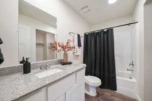 Bathroom featuring a single vanity with a granite-style countertop, undermount sink, and chrome faucet