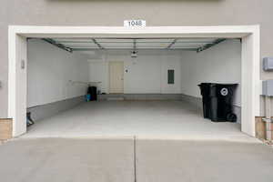 Attached garage with a light gray epoxy floor coating, white interior walls, and a light-colored entry door